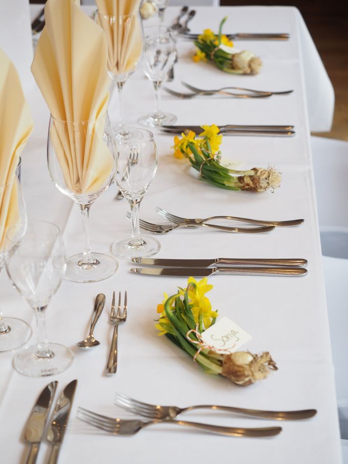 A long white table with silverware and flowers on it