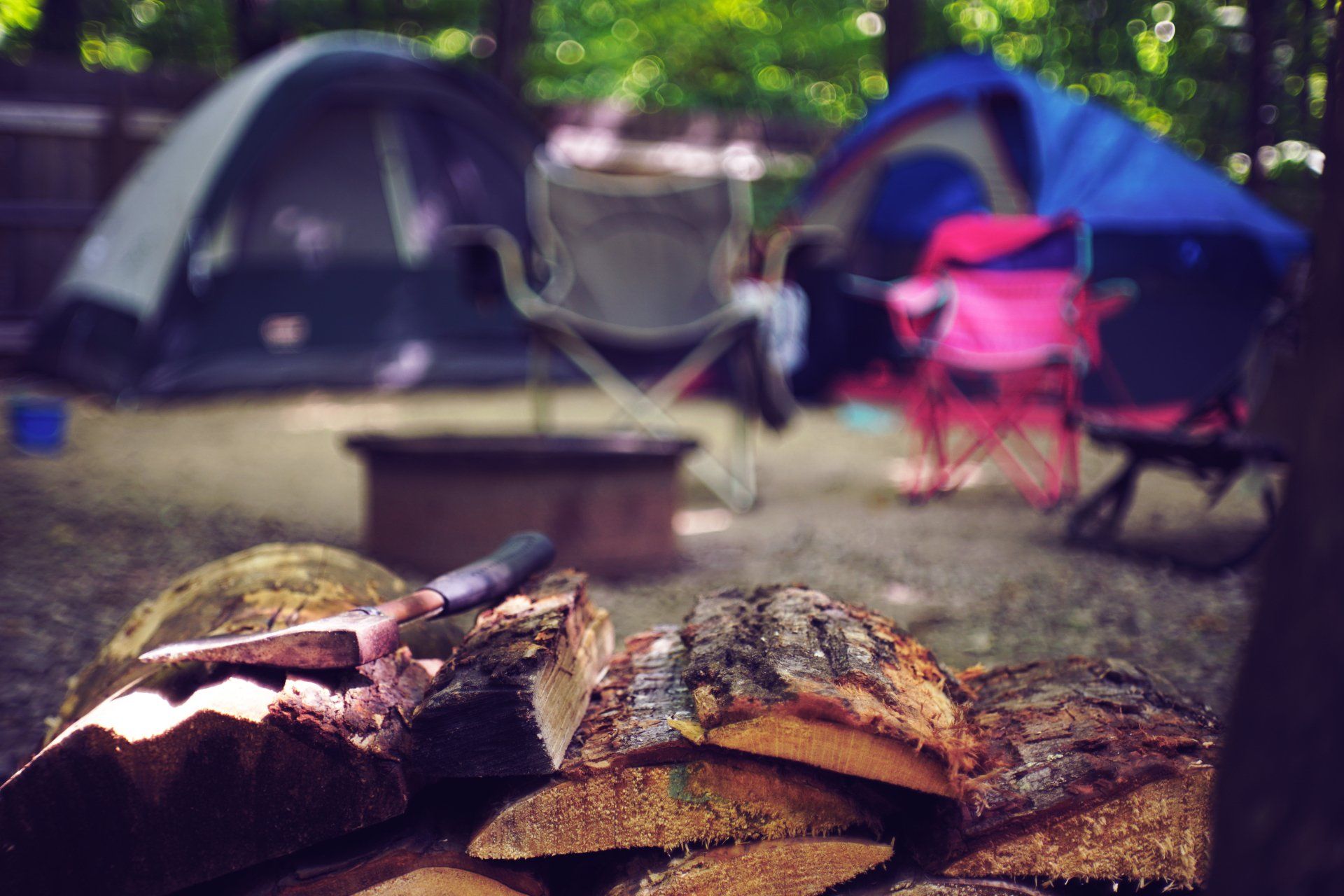 A pile of wood is sitting in front of a tent in a campground.