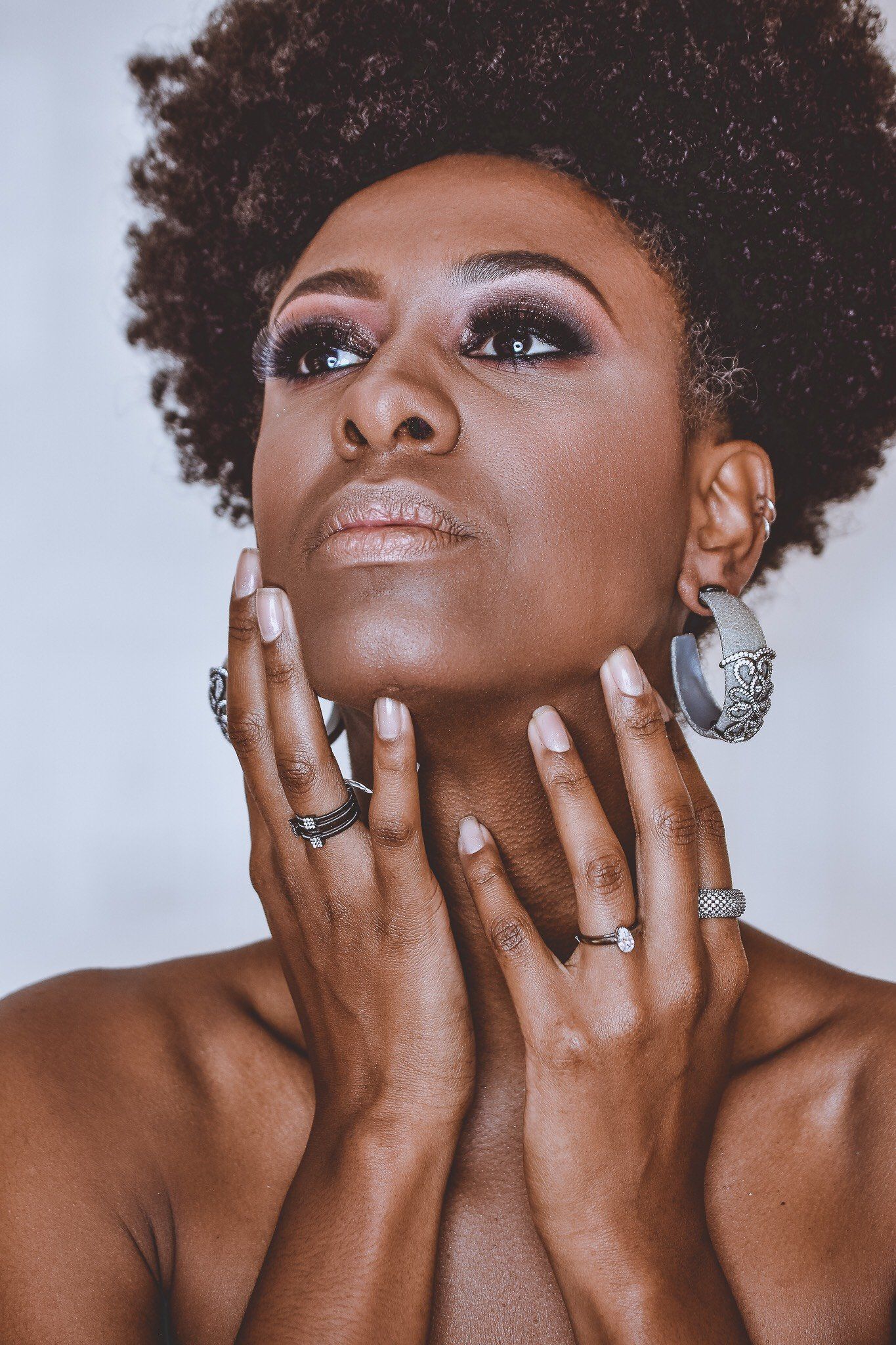 A close up of a woman 's face with rings on her fingers