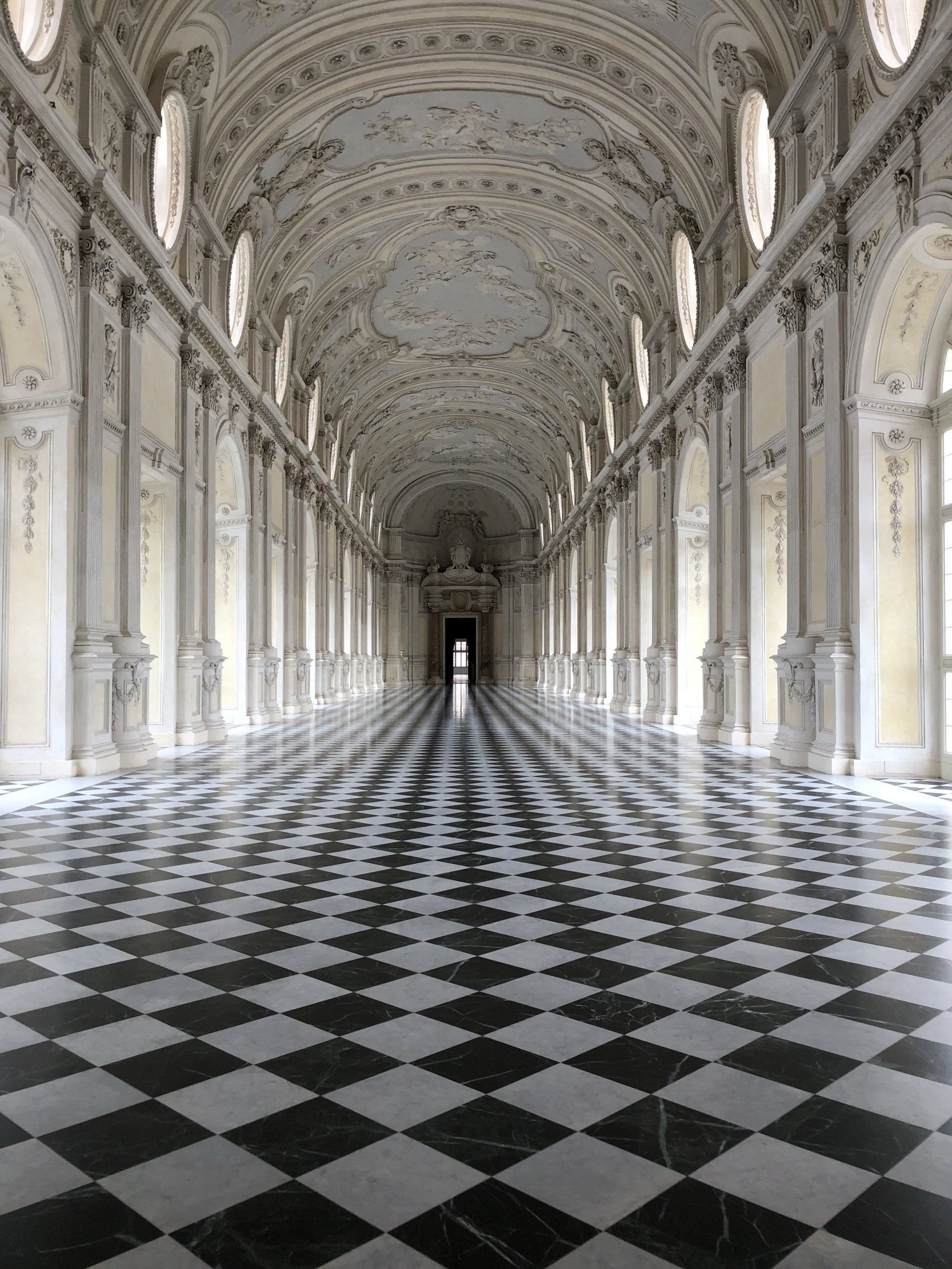 a long hallway with a checkered floor and columns