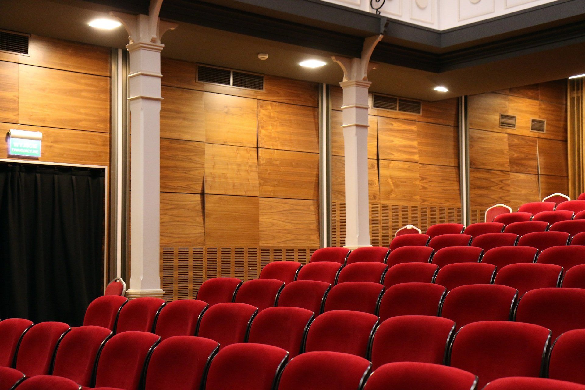 Rows of red seats in an auditorium with wooden walls