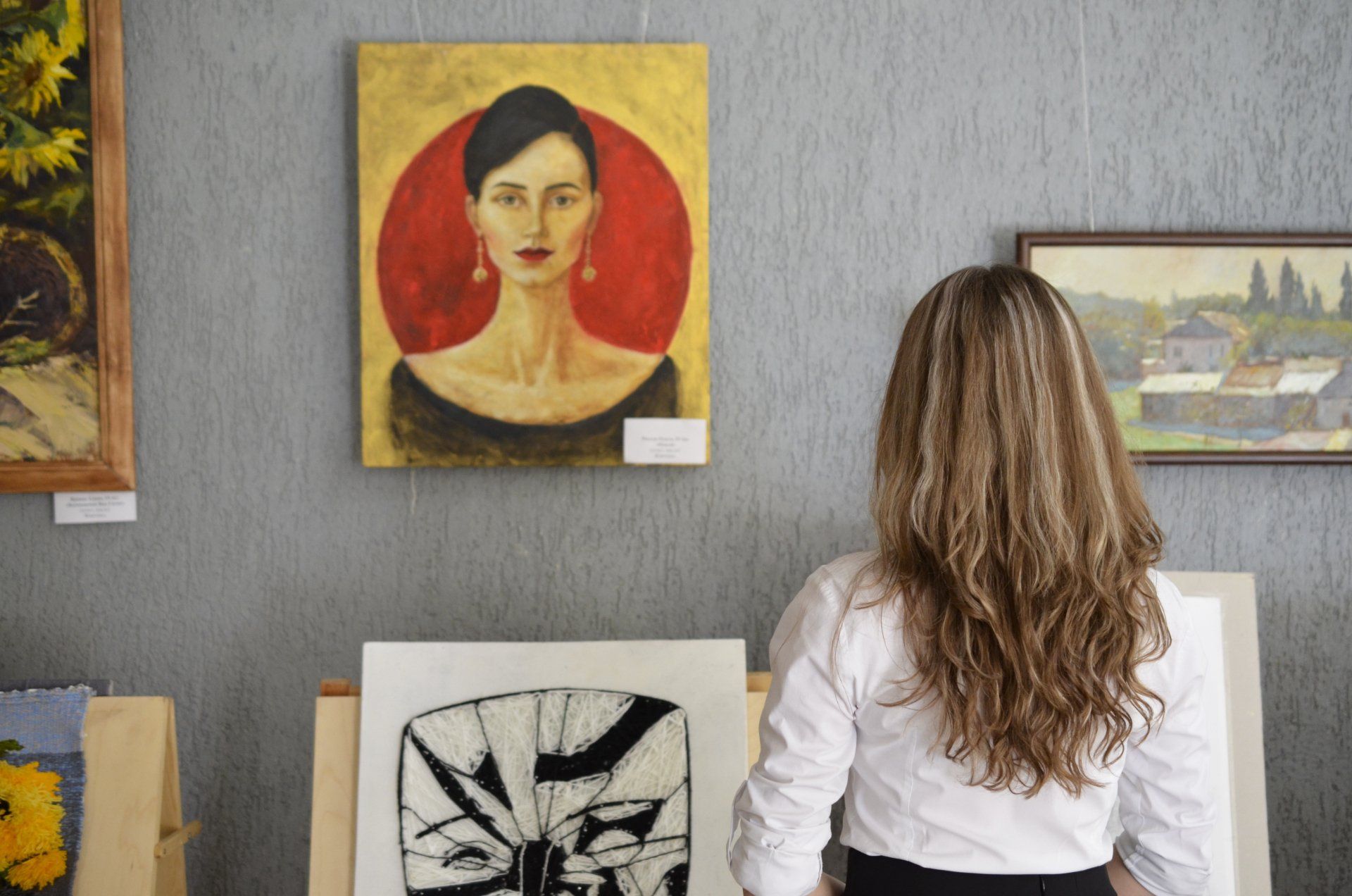 a woman is looking at a painting of a woman in a museum .