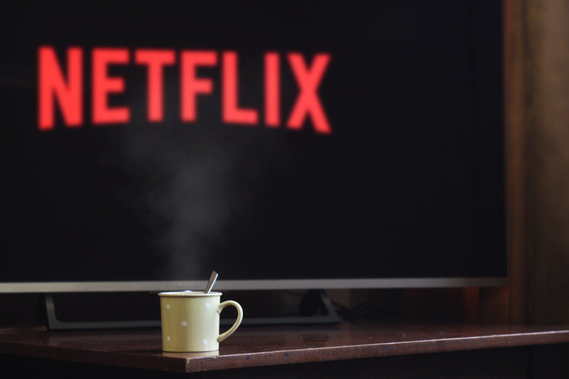 una tazza di caffè davanti a un televisore che mostra il logo di Netflix