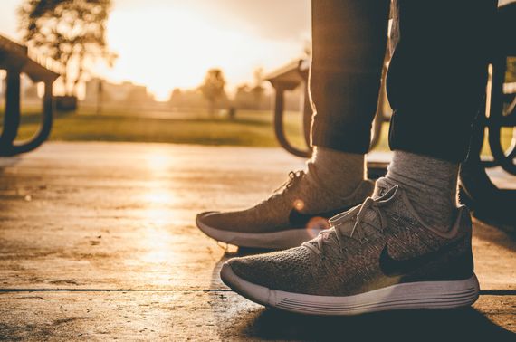 A person is standing on a sidewalk wearing sneakers.