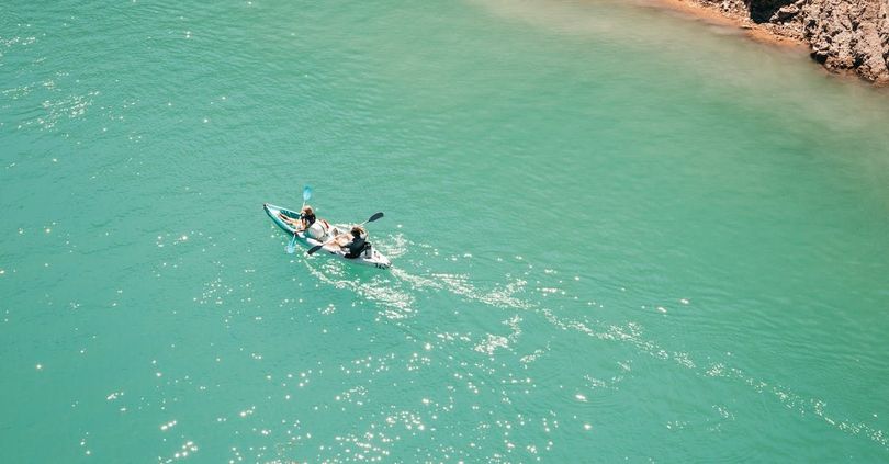 An aerial view of two people in a kayak in the ocean.