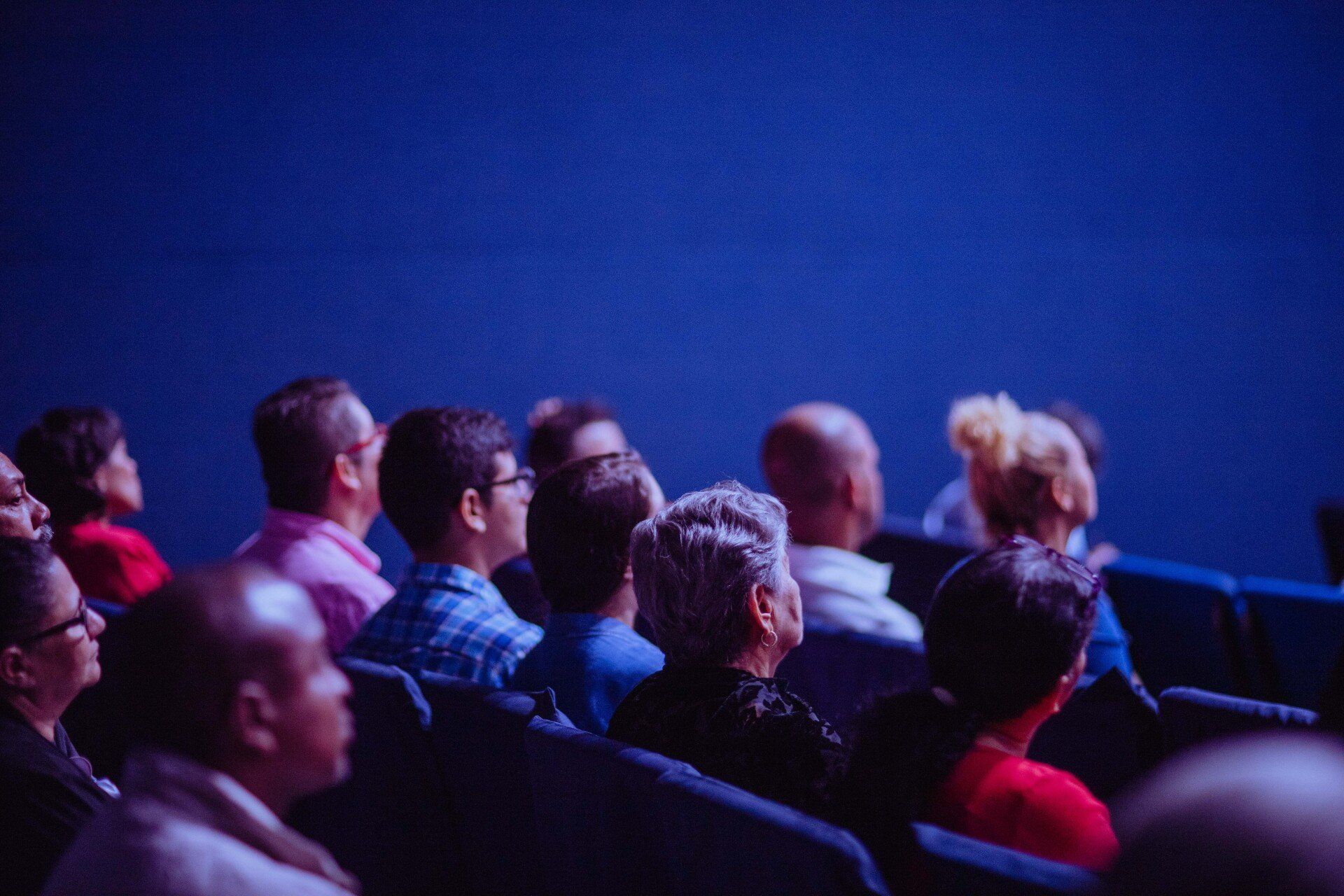 a group of people are sitting in a theater watching a movie .