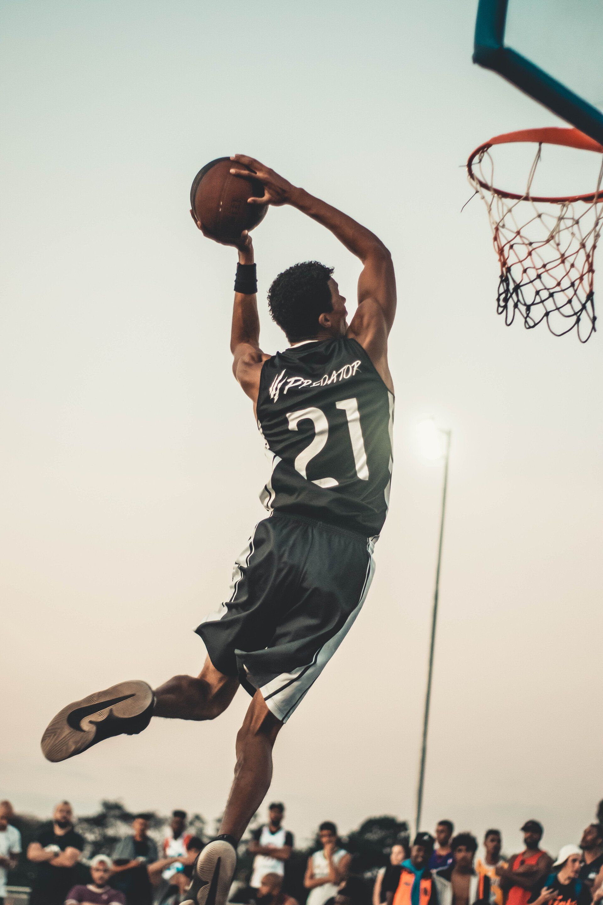 a man wearing a number 21 jersey is jumping in the air to dunk a basketball