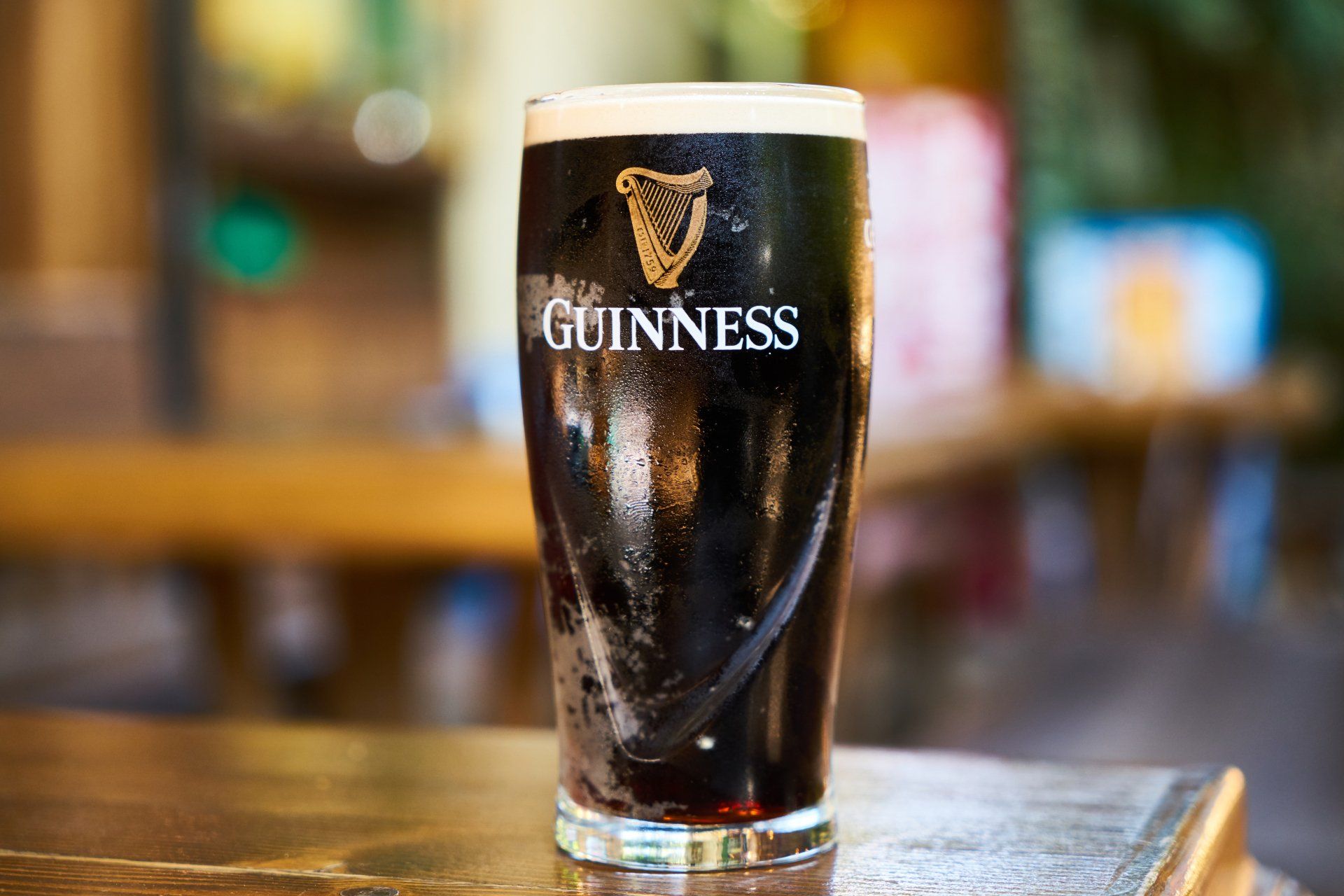 a glass of guinness beer is sitting on a wooden table .