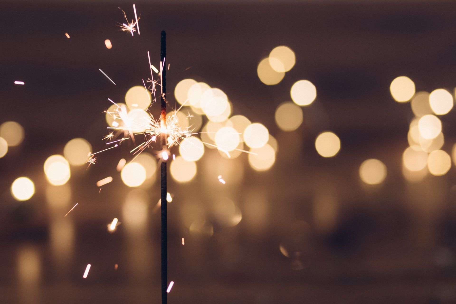 A close up of a sparkler with lights in the background.