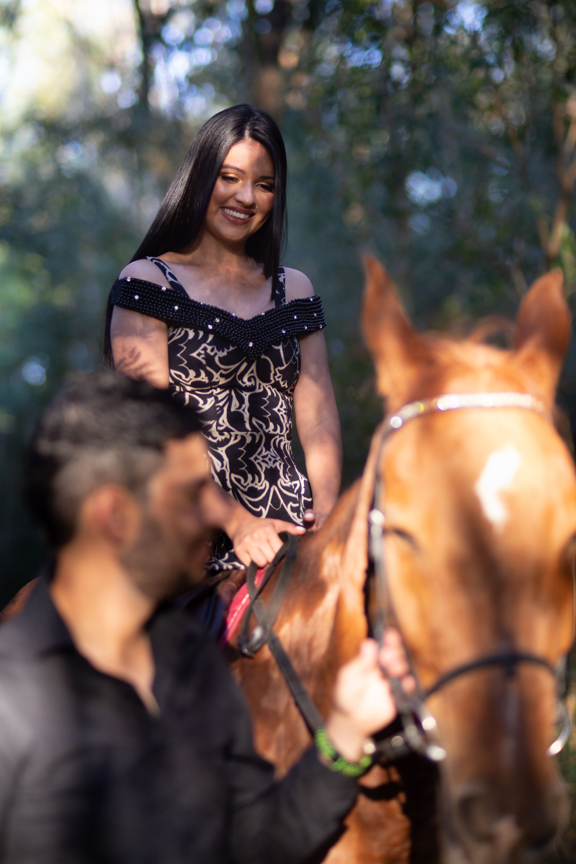 A man and a woman are riding a horse in the woods.