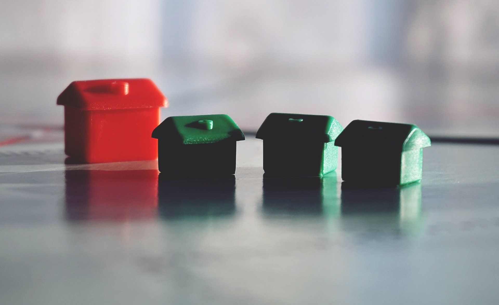 A red , green , and black toy house are sitting on a table.