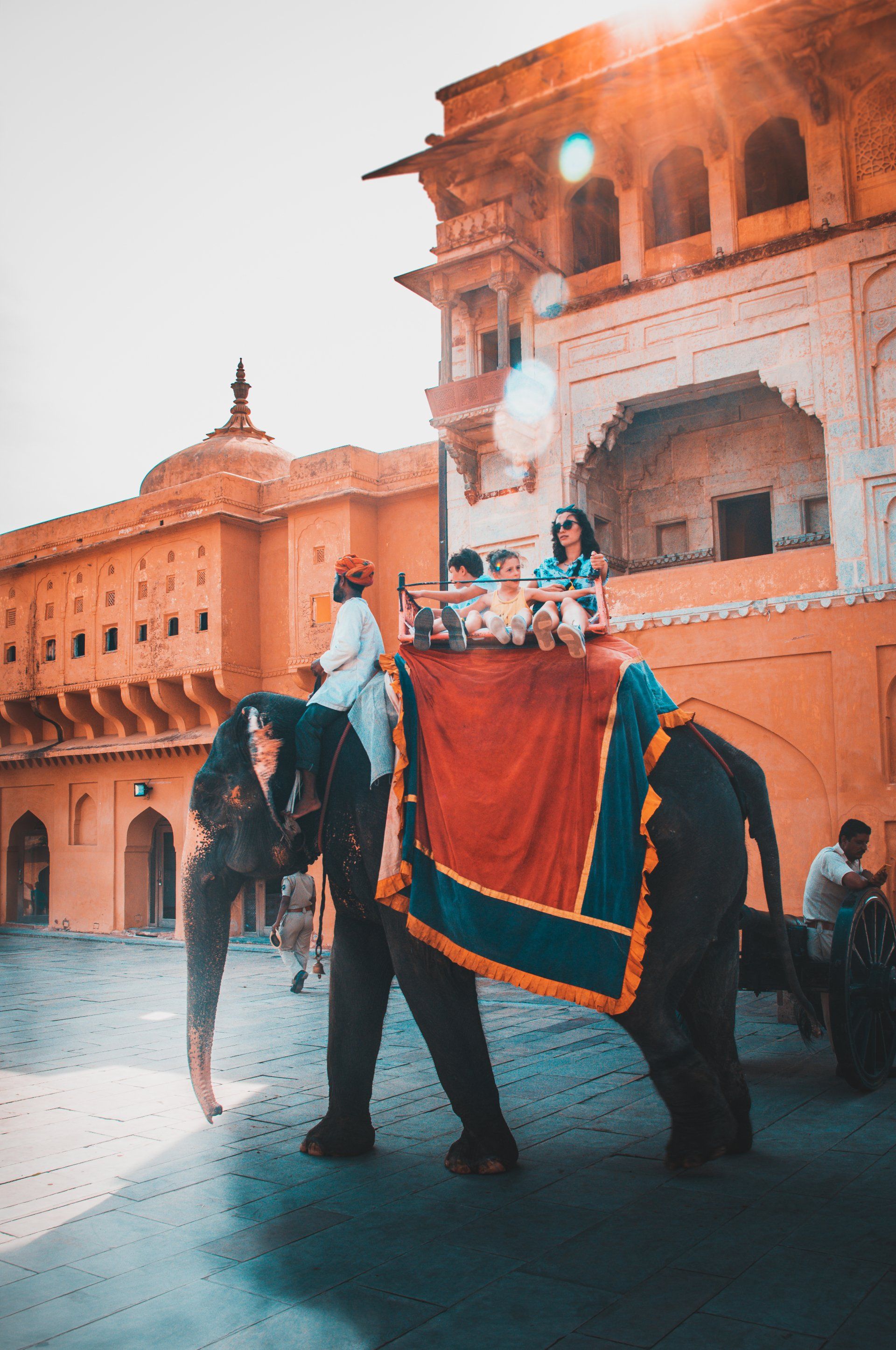 A group of people are riding on the back of an elephant in front of a building.