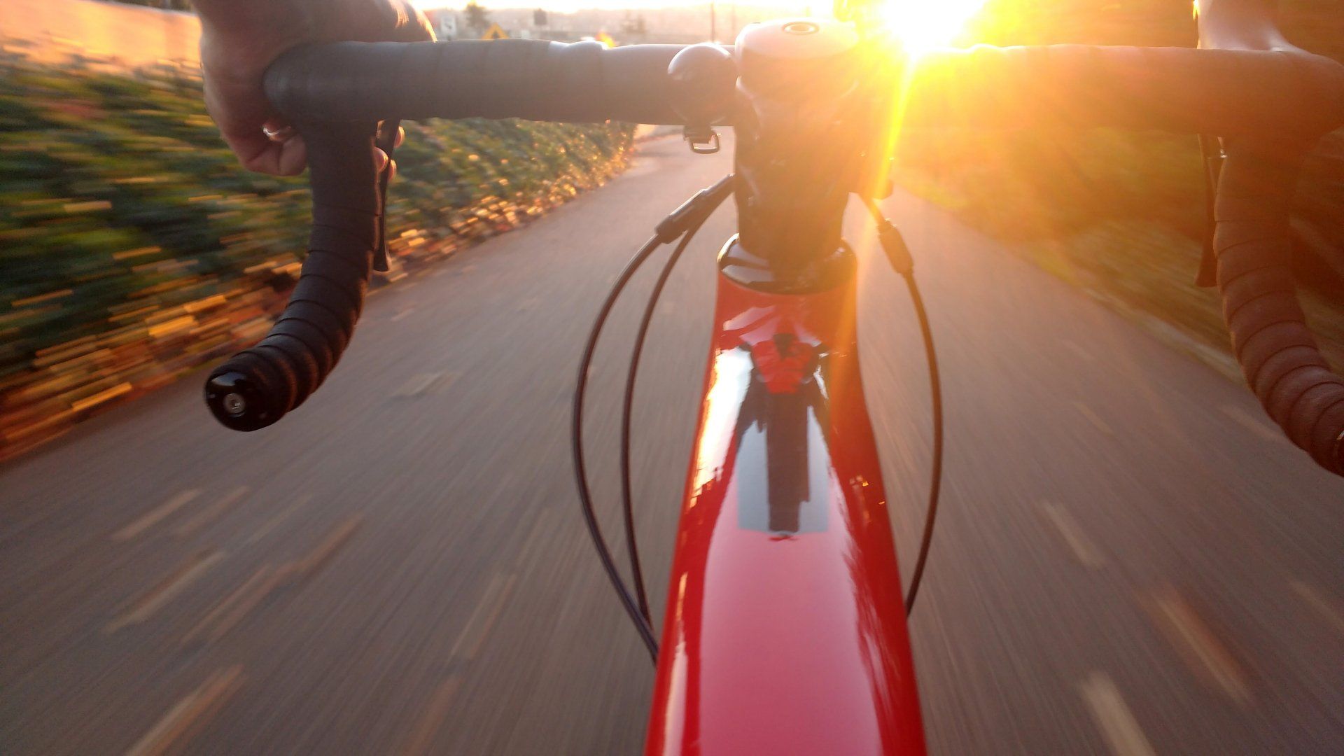 a person is riding a bicycle down a road at sunset .