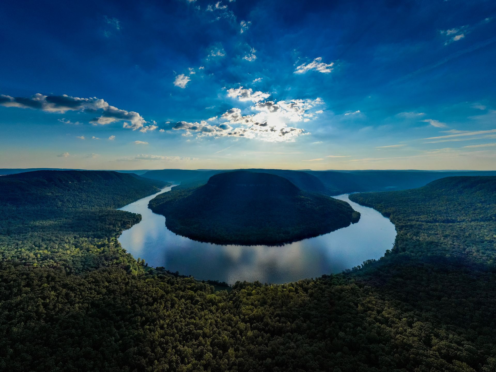 An aerial view of a river surrounded by trees and mountains