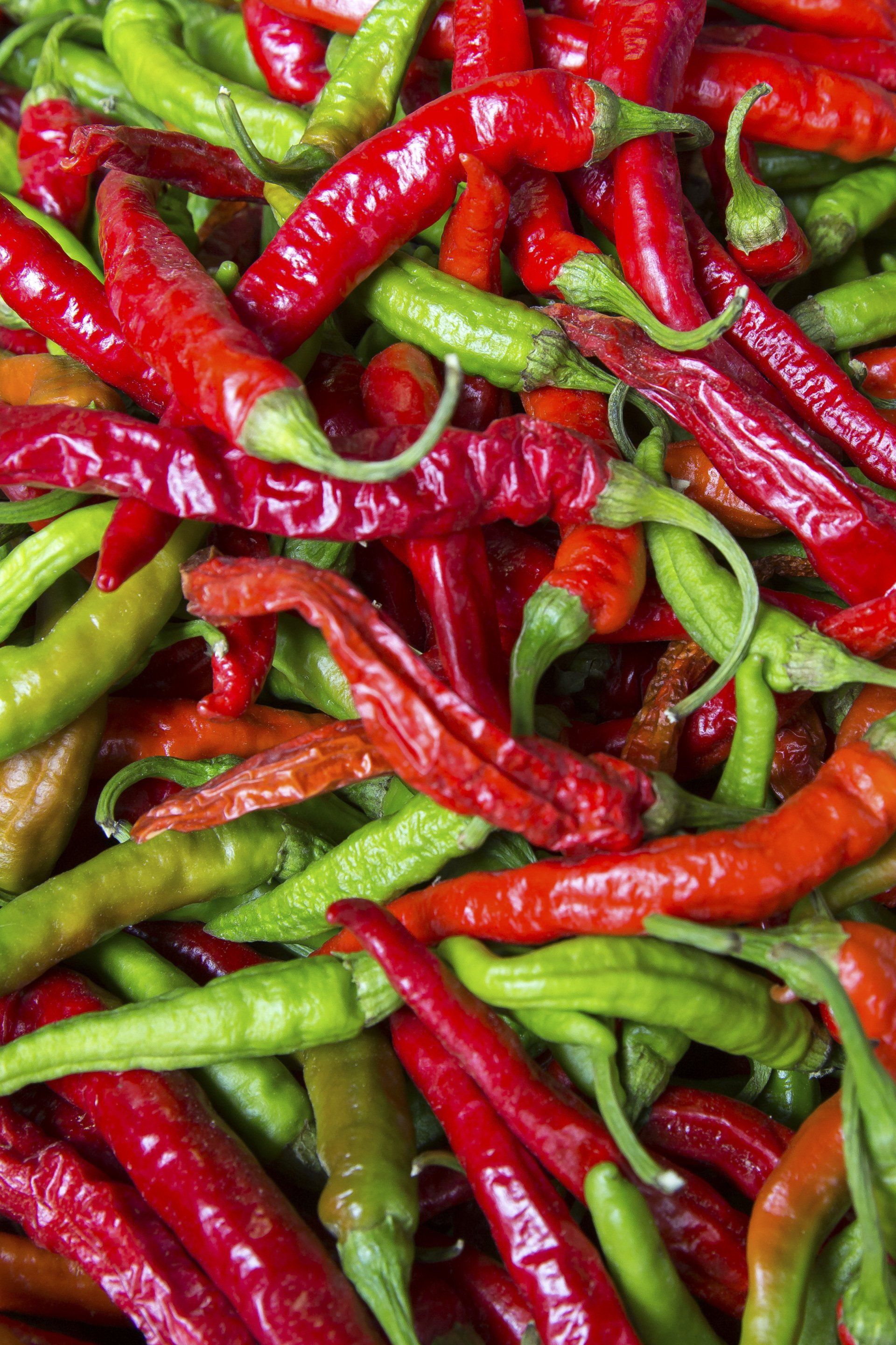 a pile of red and green peppers are stacked on top of each other .