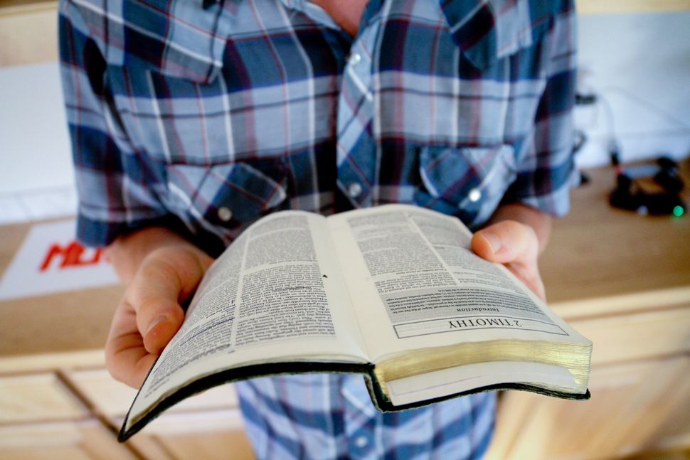 A man in a plaid shirt is holding a bible in his hands.