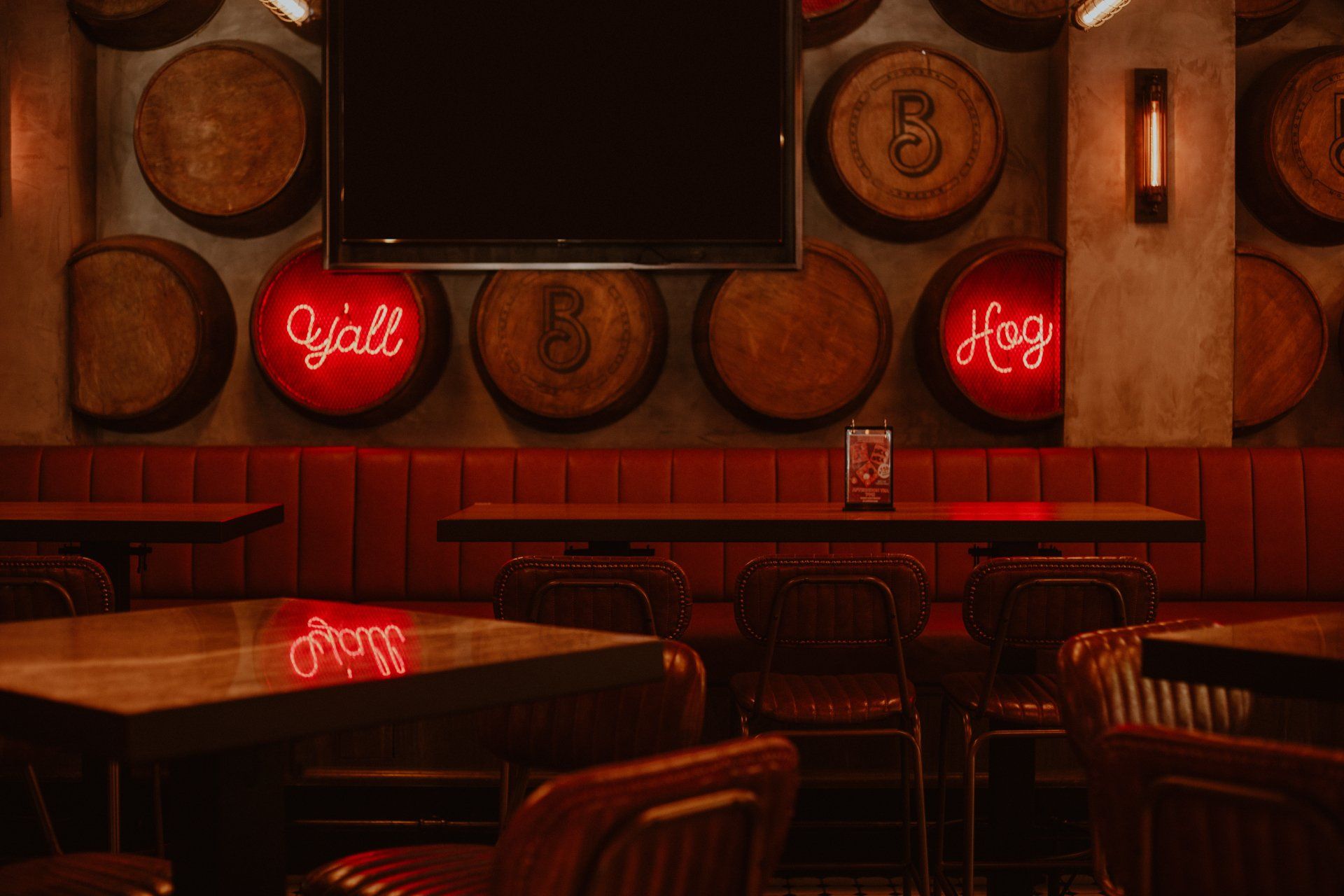 A restaurant with tables and chairs and barrels on the wall.