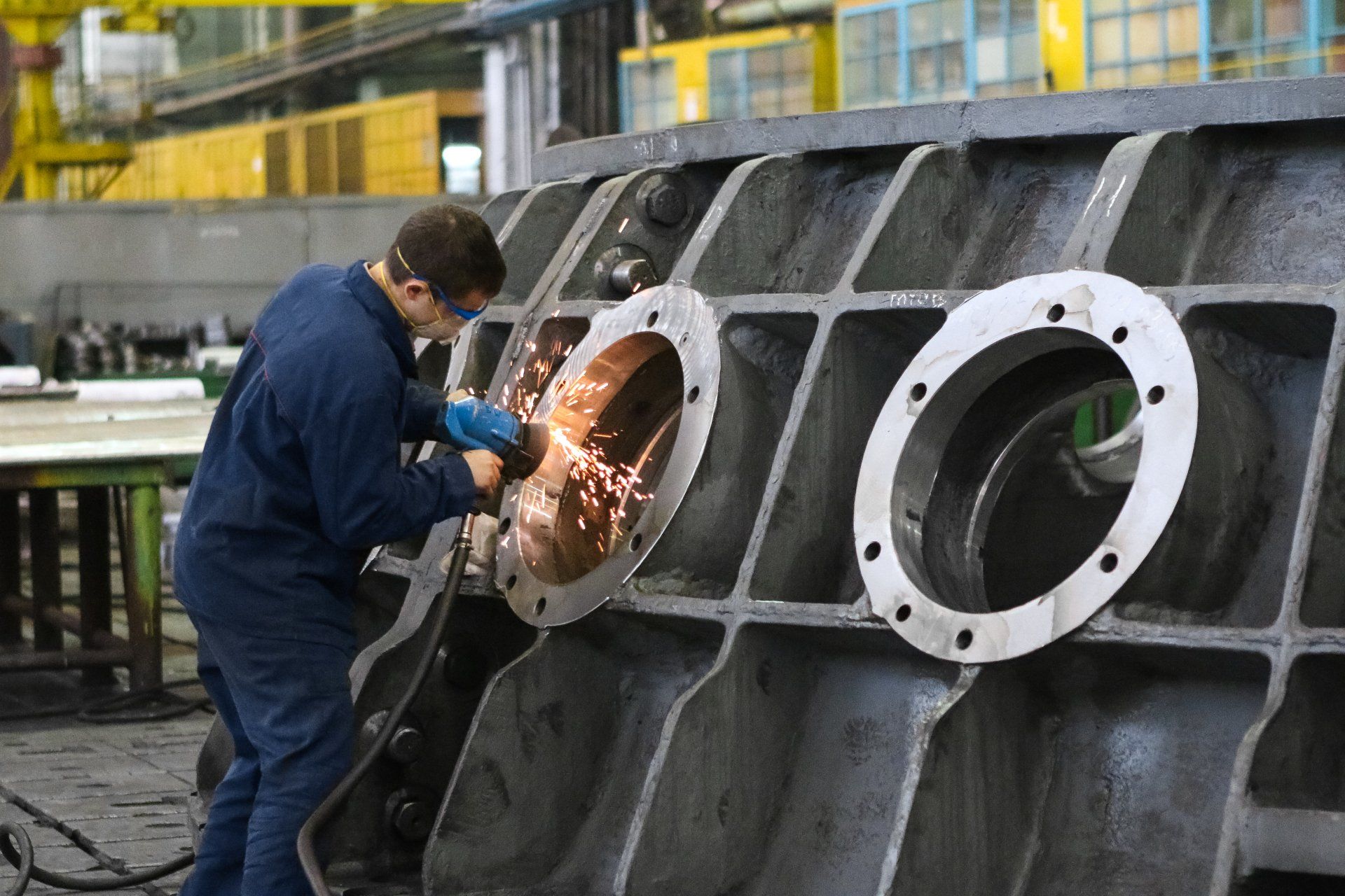 a man is grinding a piece of metal in a factory.