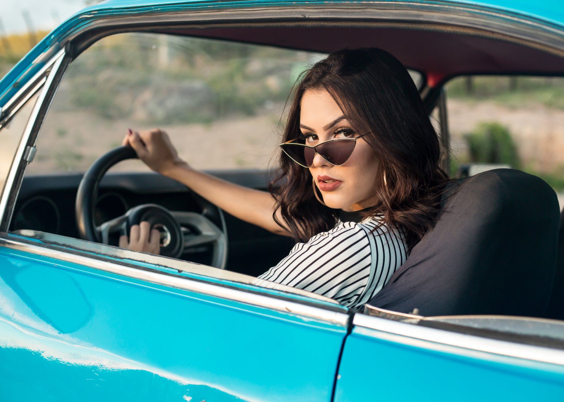 Woman in blue car wearing sunglasses
