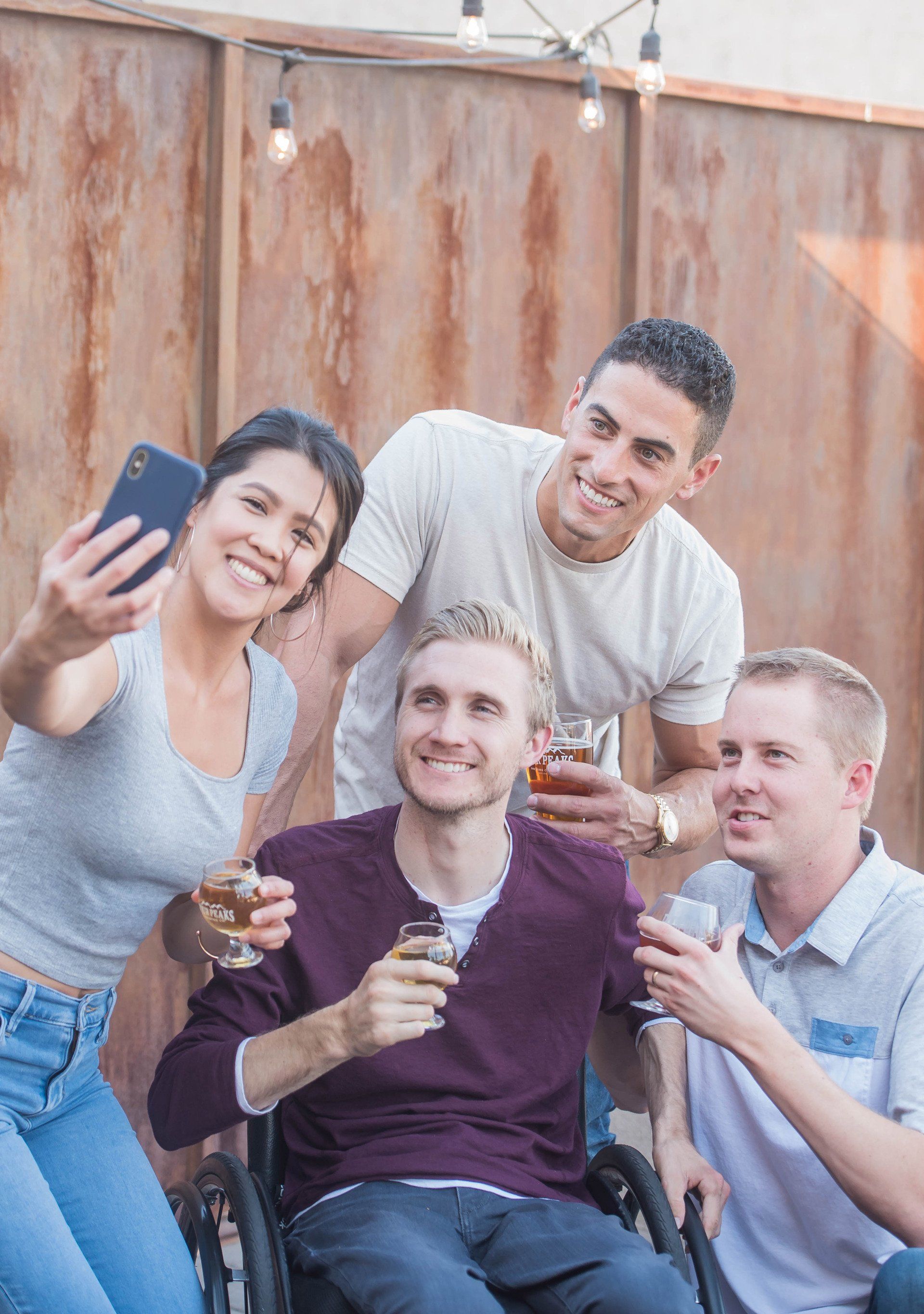 A group of people are taking a selfie with a man in a wheelchair.