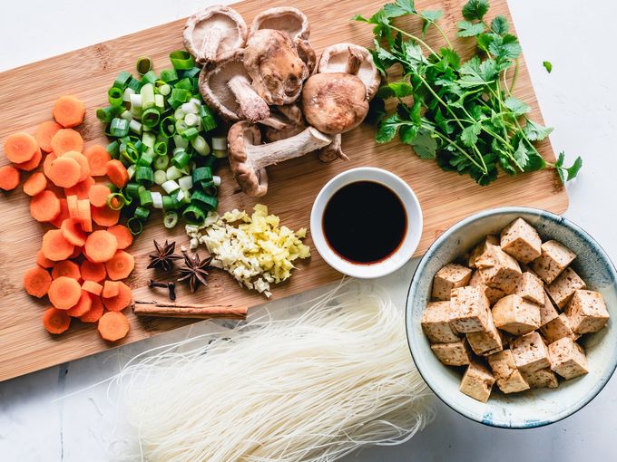 A wooden cutting board topped with a variety of vegetables and tofu.