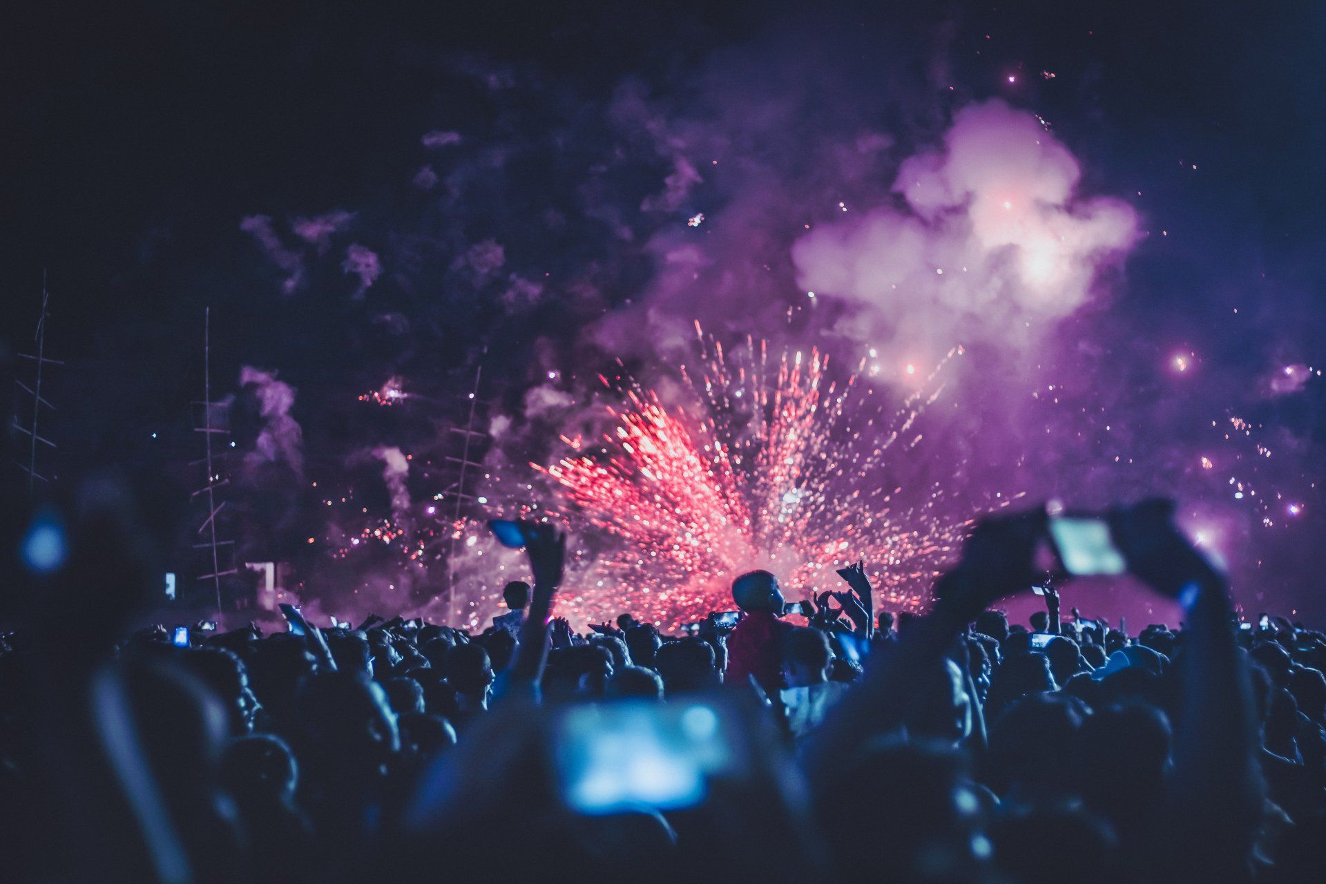 A crowd of people are watching fireworks in the night sky.