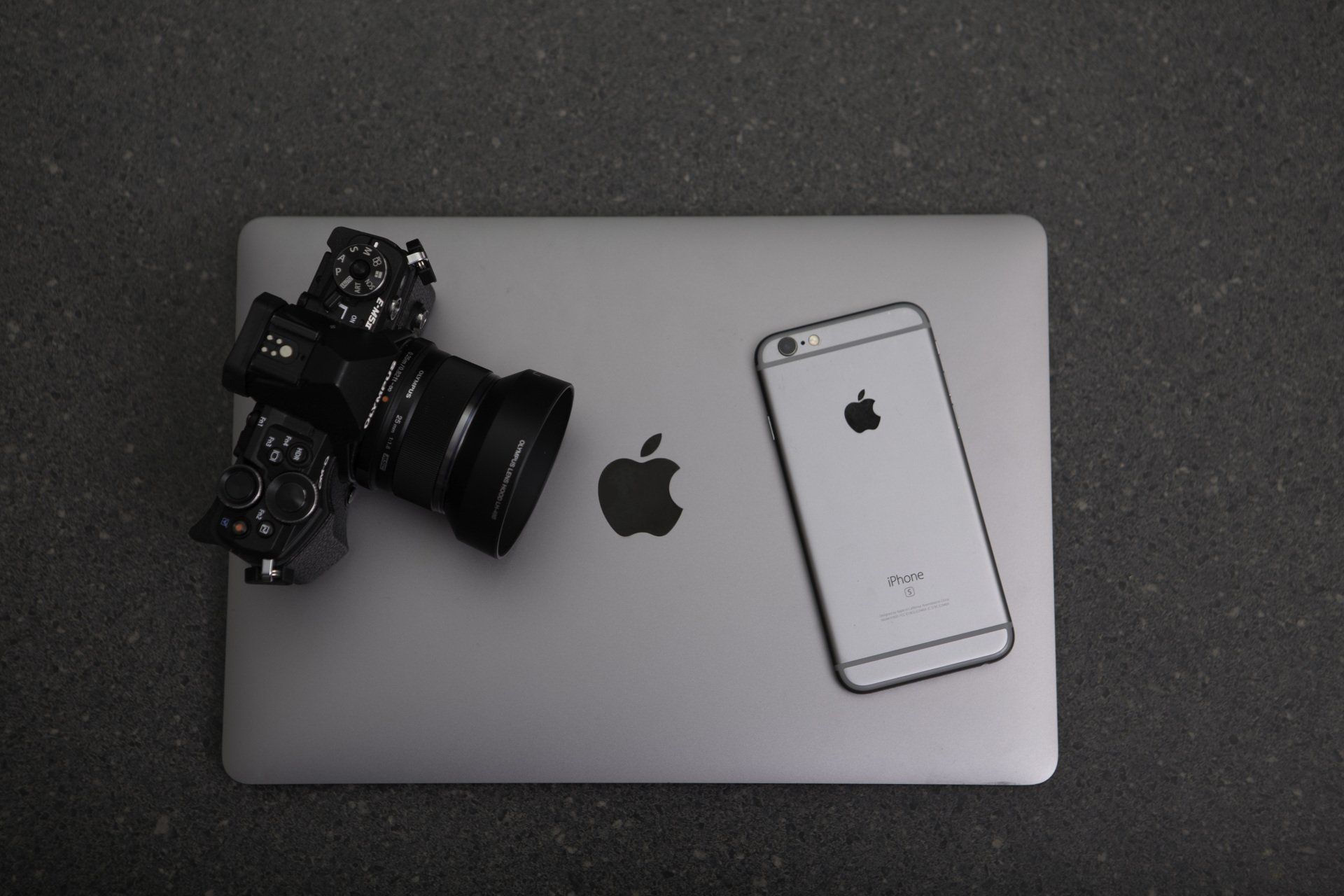 an apple laptop with a camera and a cell phone on it .