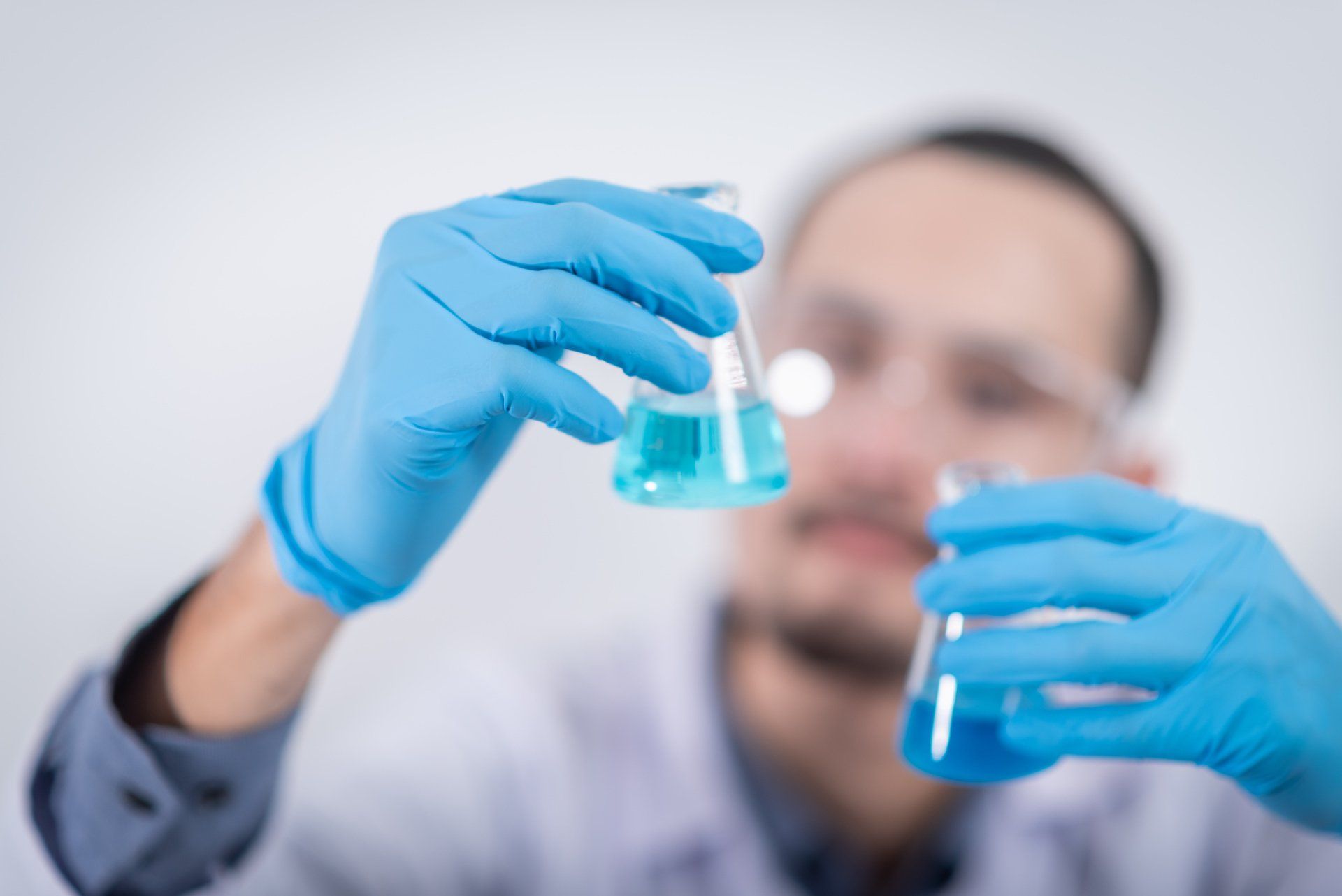 Uno scienziato tiene in mano un bicchiere contenente un liquido blu.