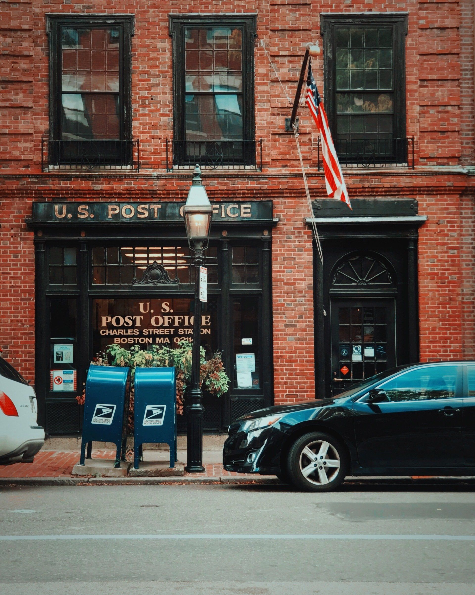 A black car is parked in front of the u.s. post office