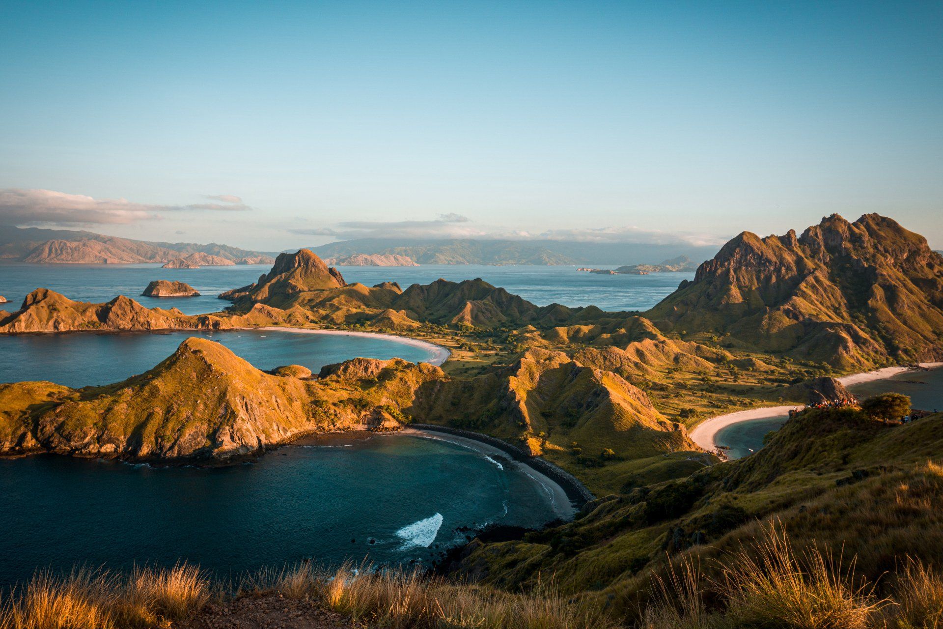 A view of a small island in the middle of the ocean with mountains in the background.