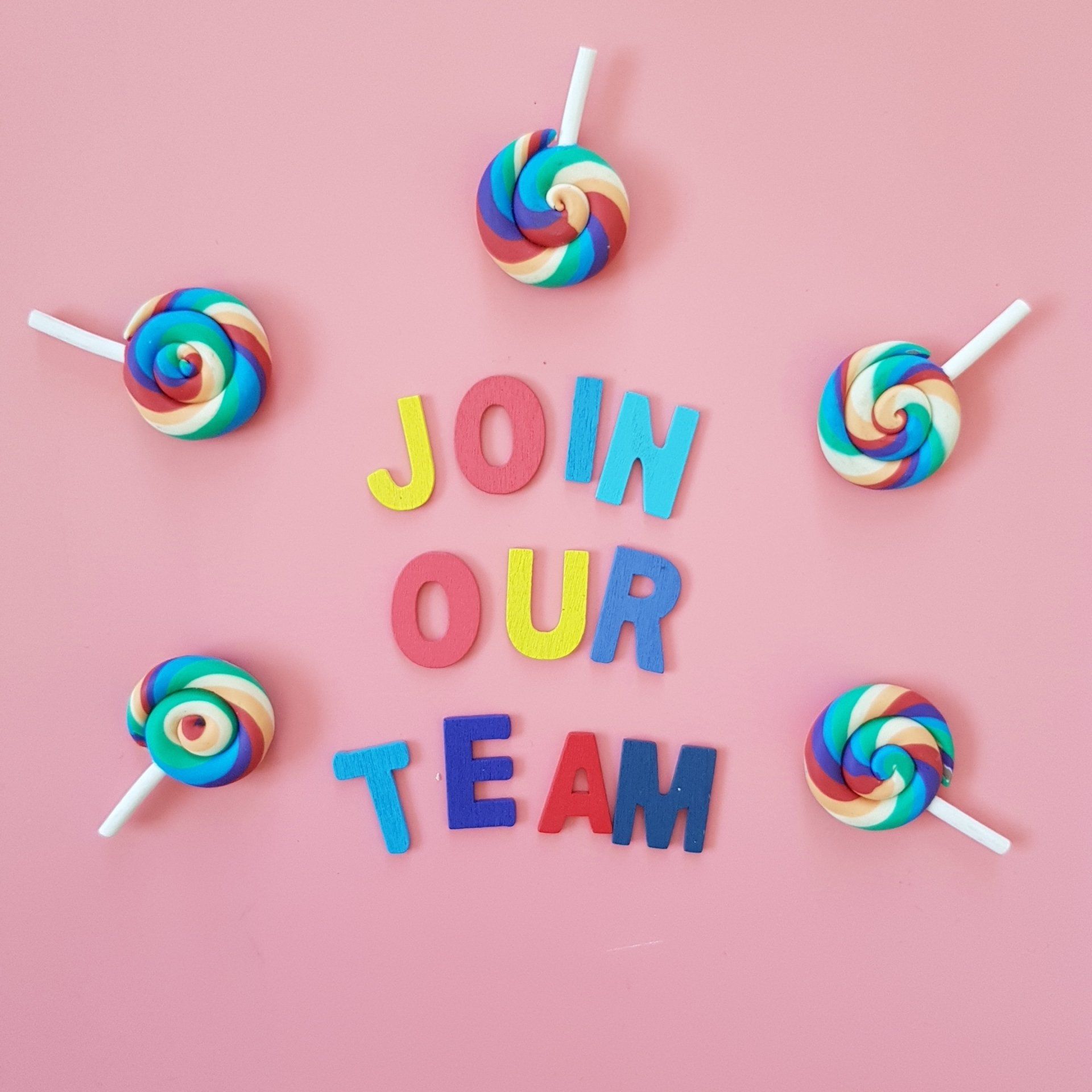 A pink background with lollipops and letters that say join our team
