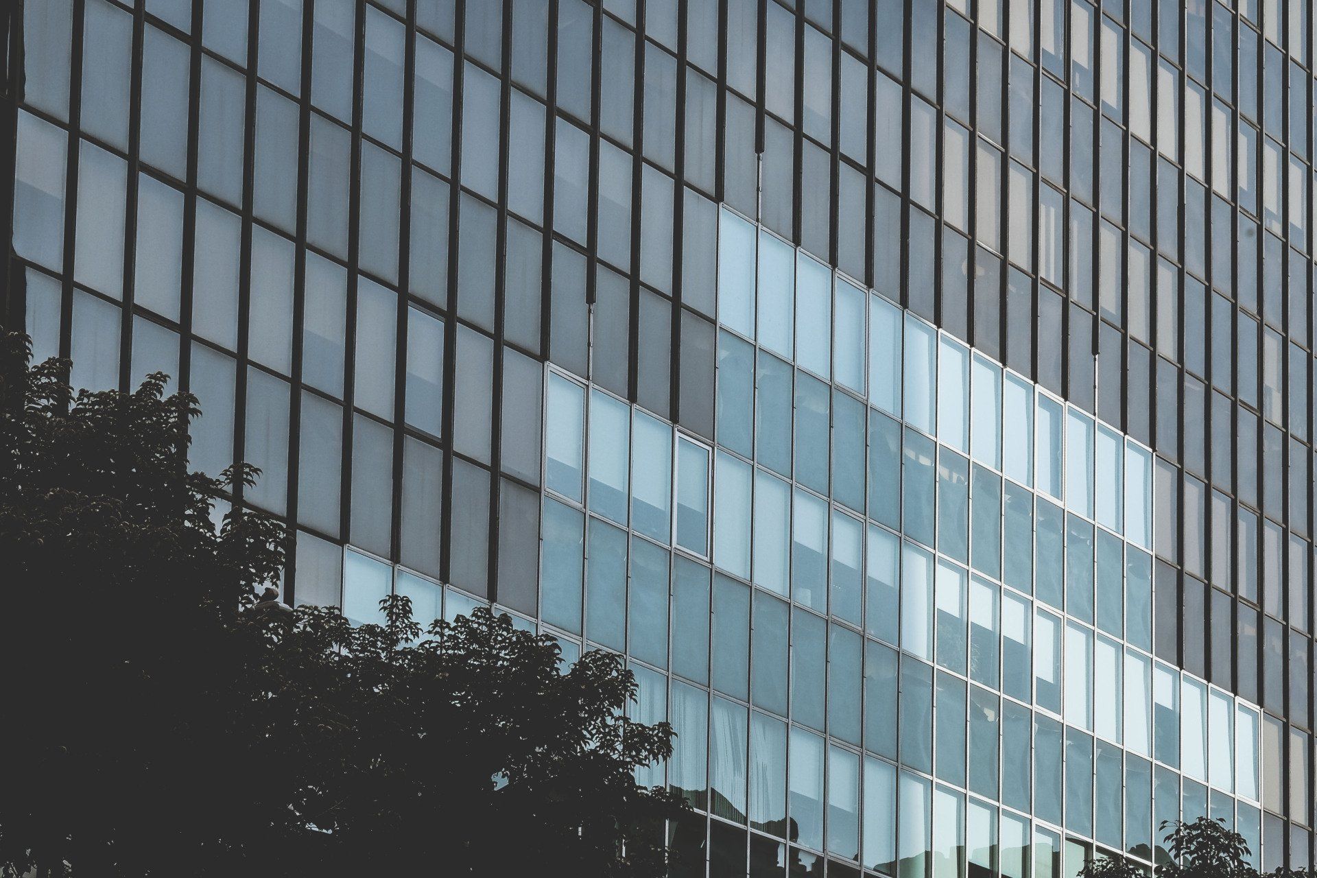 A man wearing goggles and a pencil is measuring a piece of wood.
