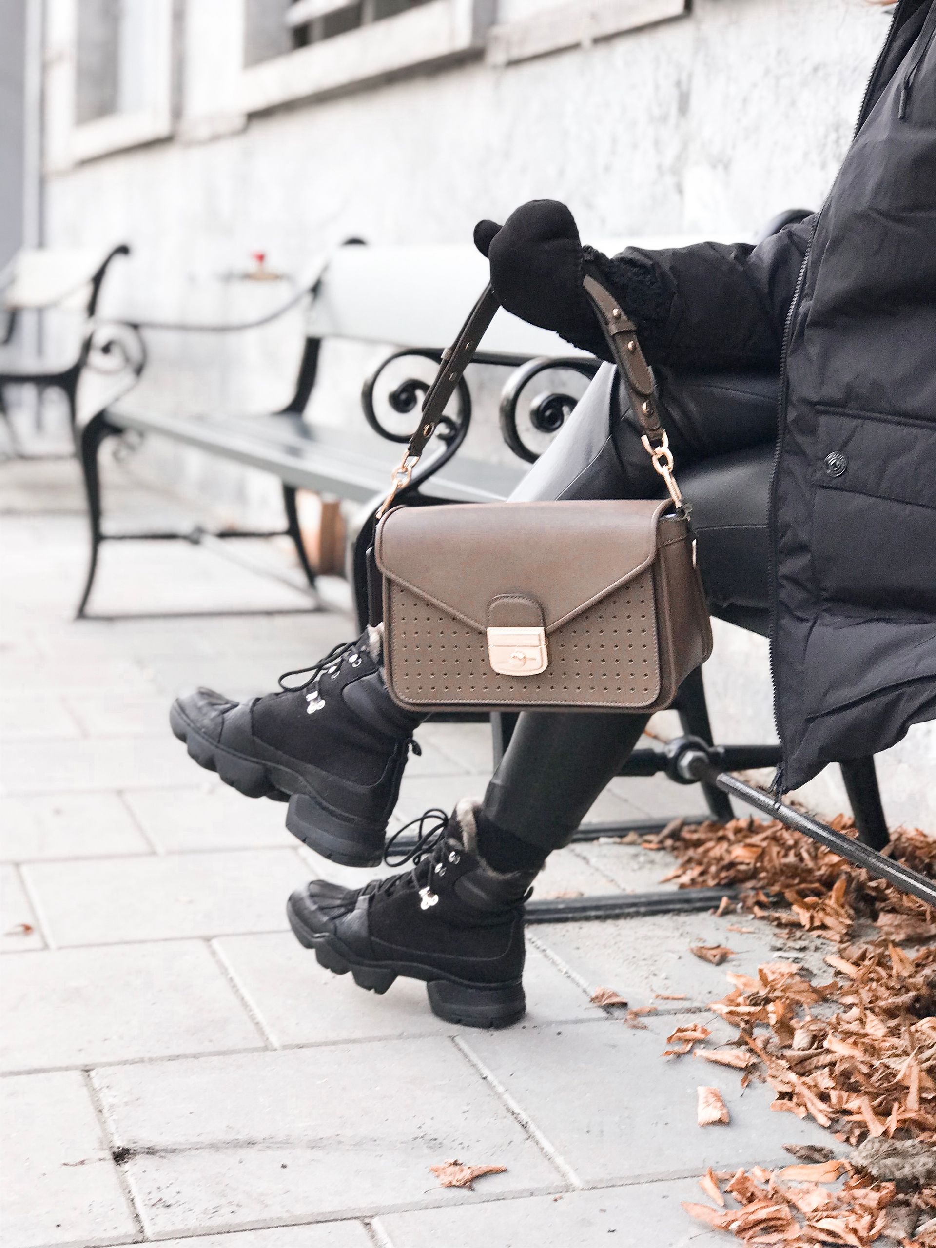 A woman is sitting on a bench holding a purse.