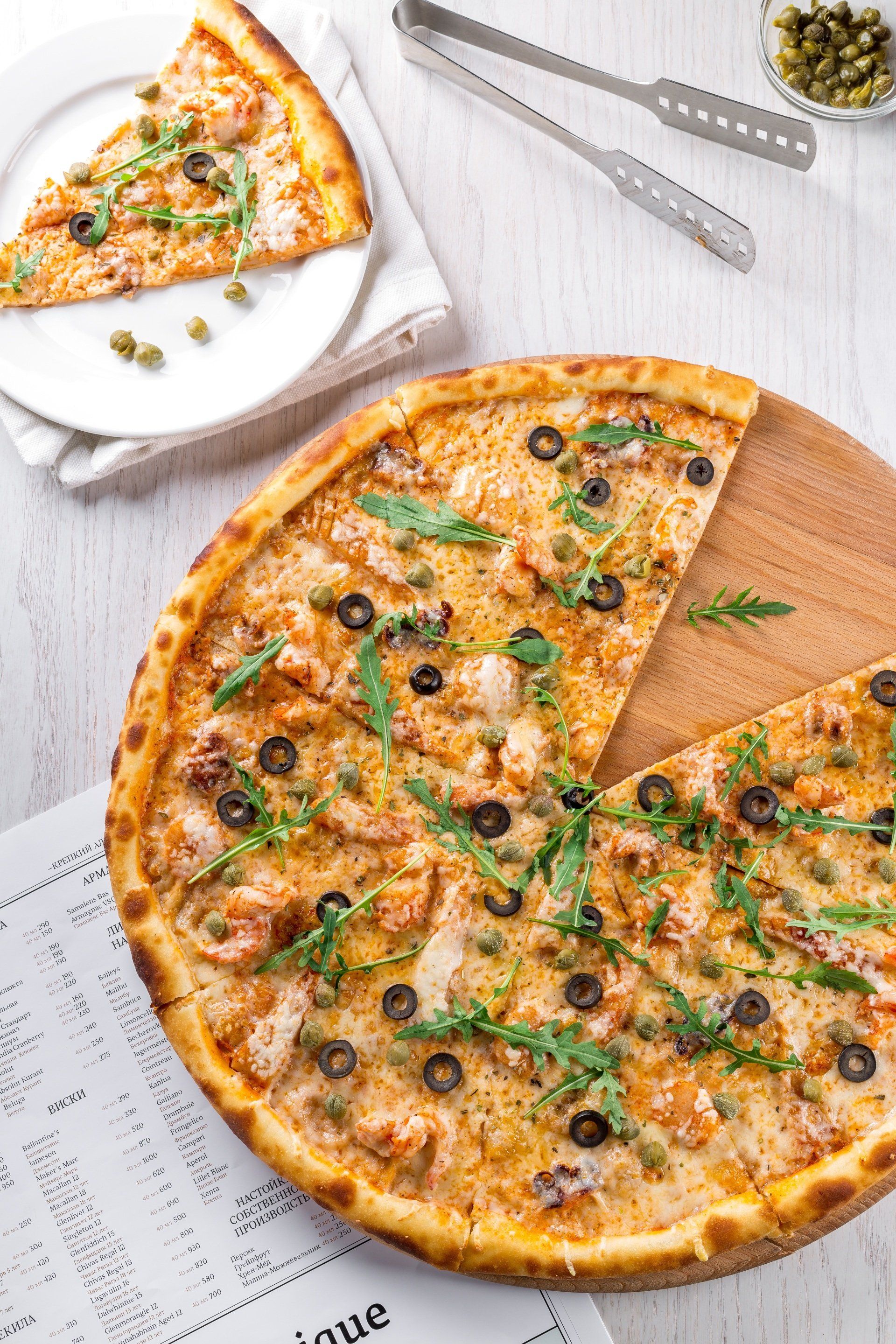 Italian-style pizza covered with fresh mozzarella, arugula, olives, and other toppings.