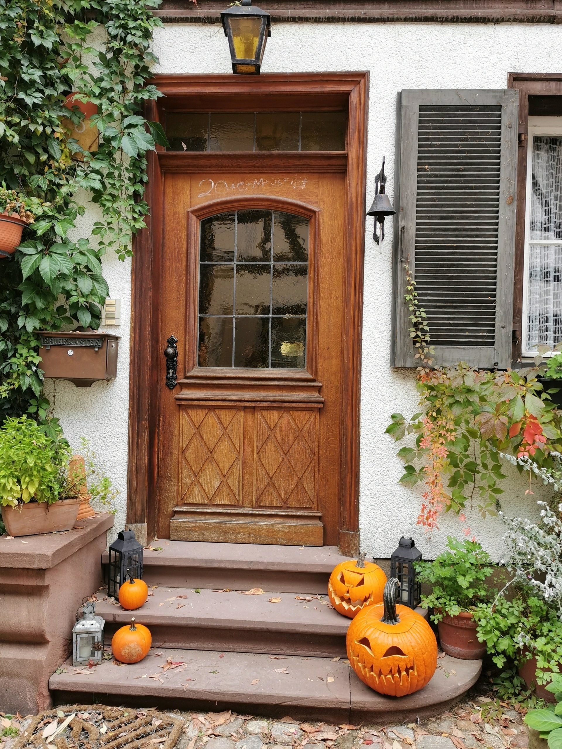 The front door of a house decorated for halloween with pumpkins and lanterns.