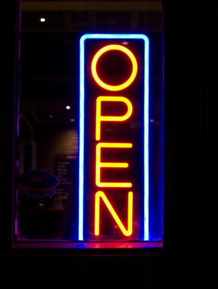 A neon sign that says open in a window