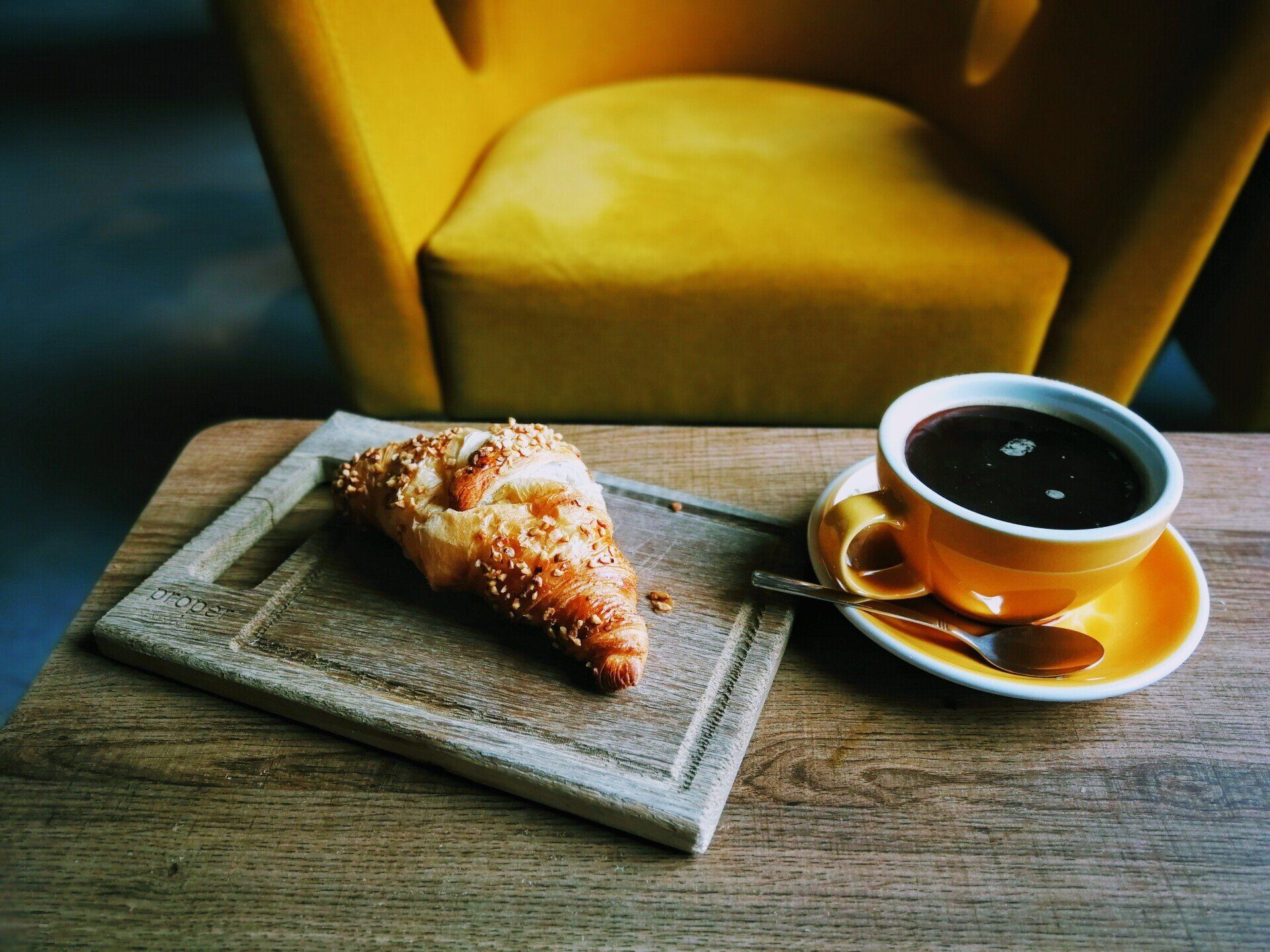 A croissant and a cup of coffee on a wooden table