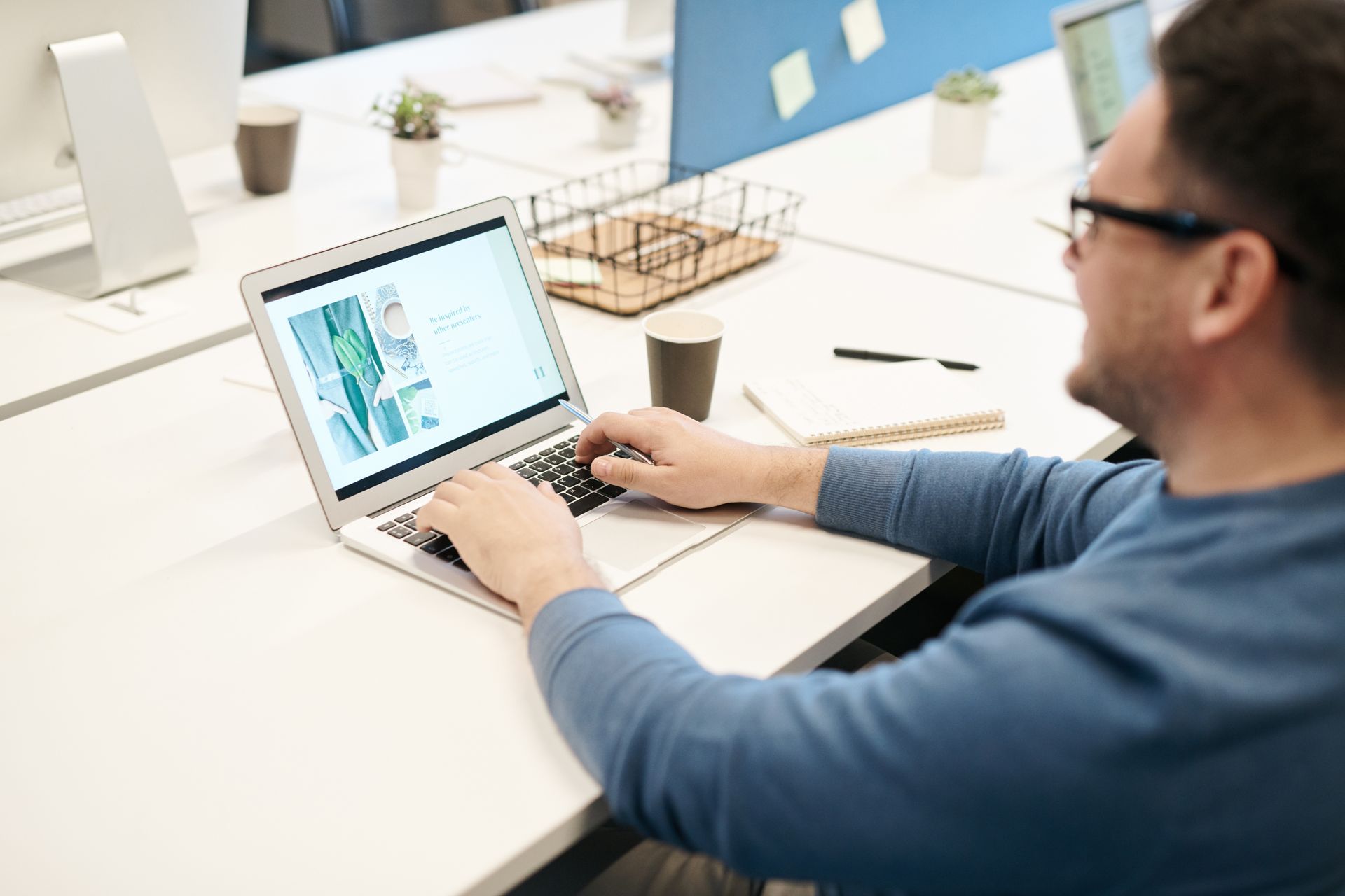 A man is sitting at a desk using a laptop computer.