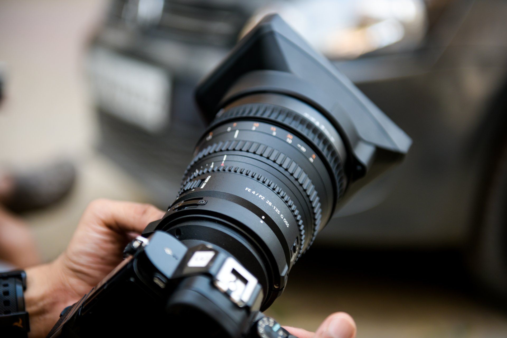 a person is holding a camera in front of a car .