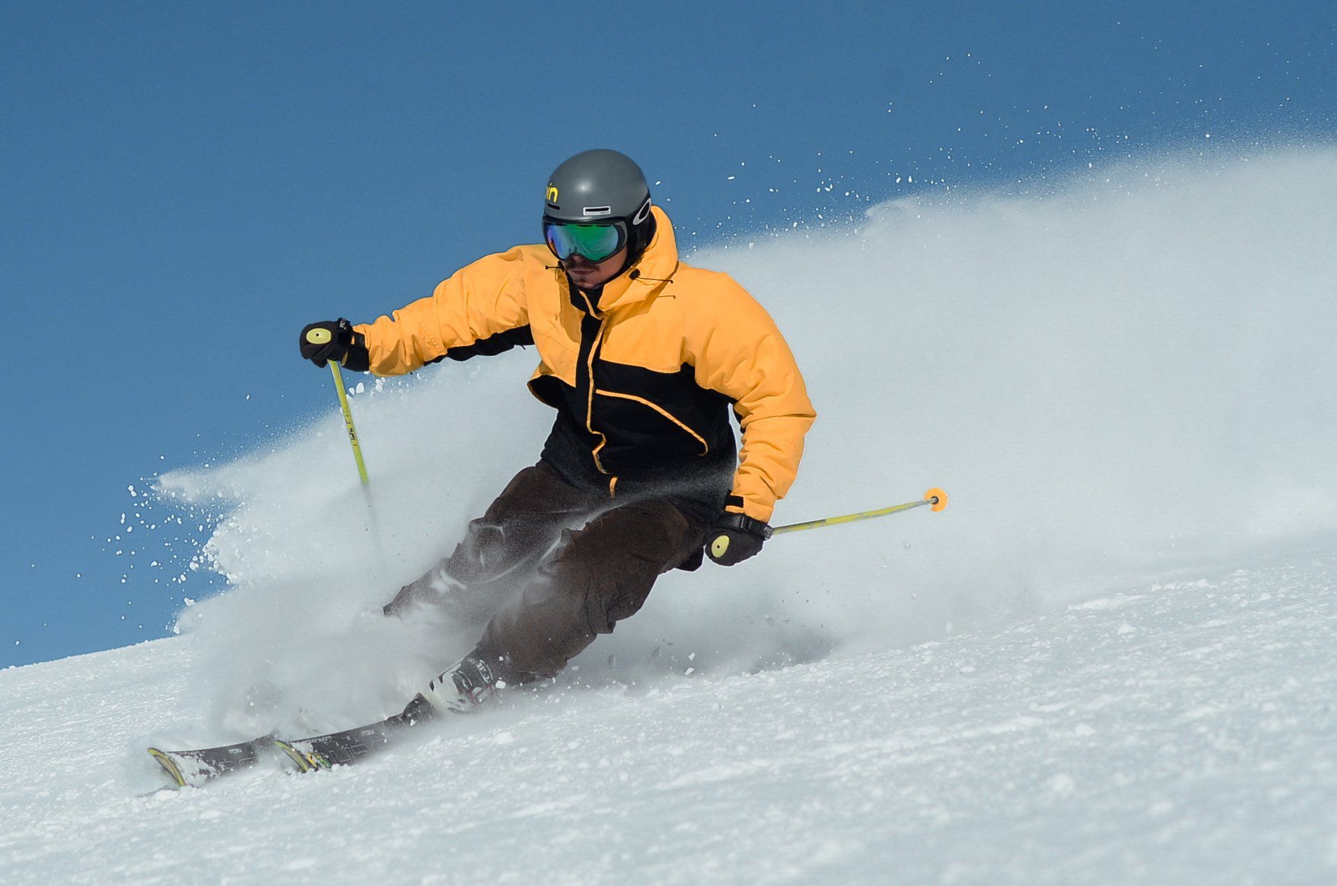 A man in a bright yellow snow jacket downhill alpine skiing