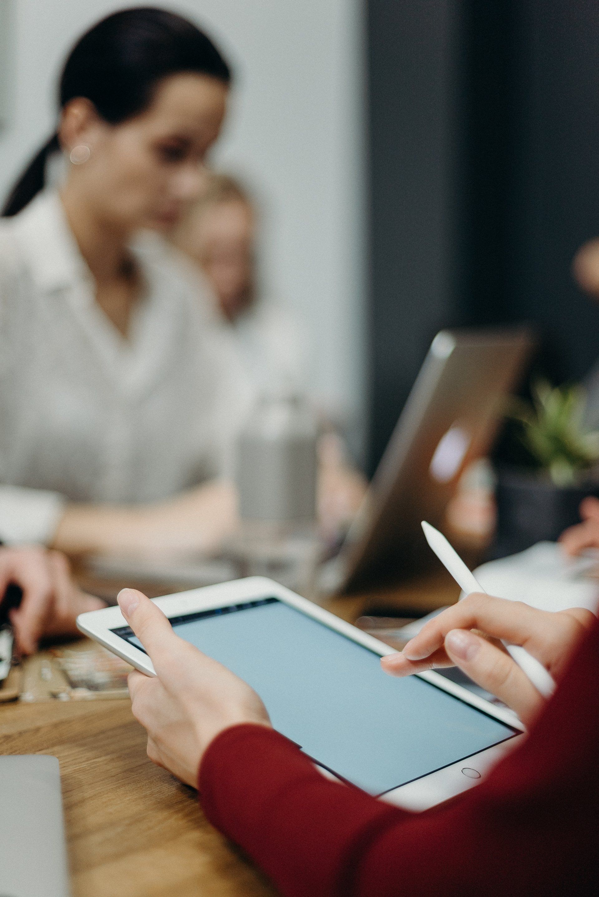 A group of people are sitting around a table with laptops and tablets.