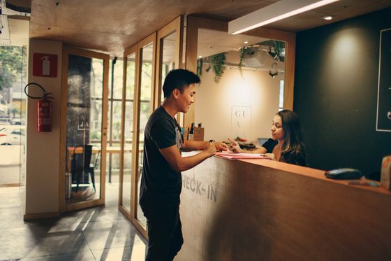 A man is standing at a reception desk talking to a woman.