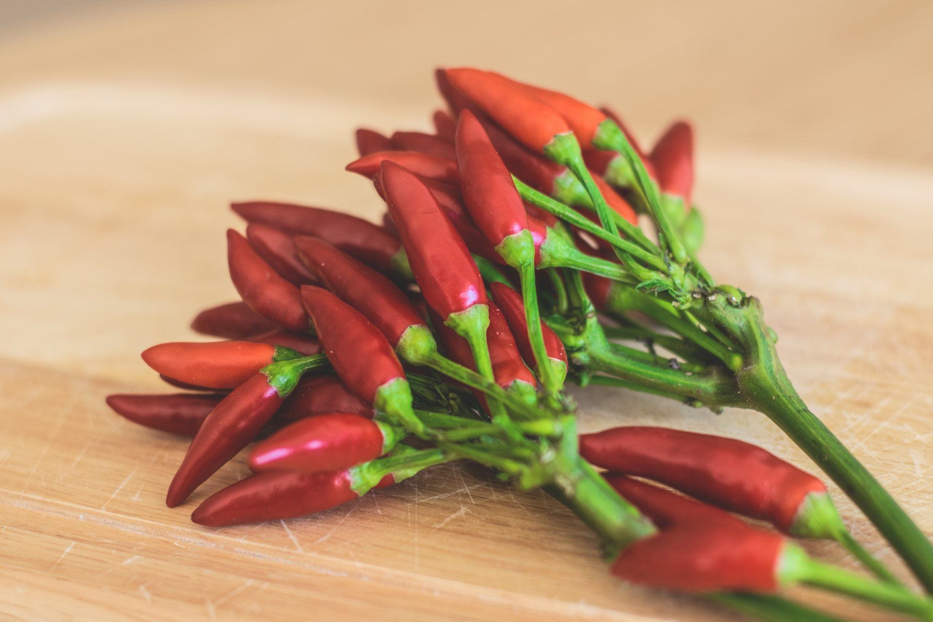 A bunch of red chili peppers on a wooden table.