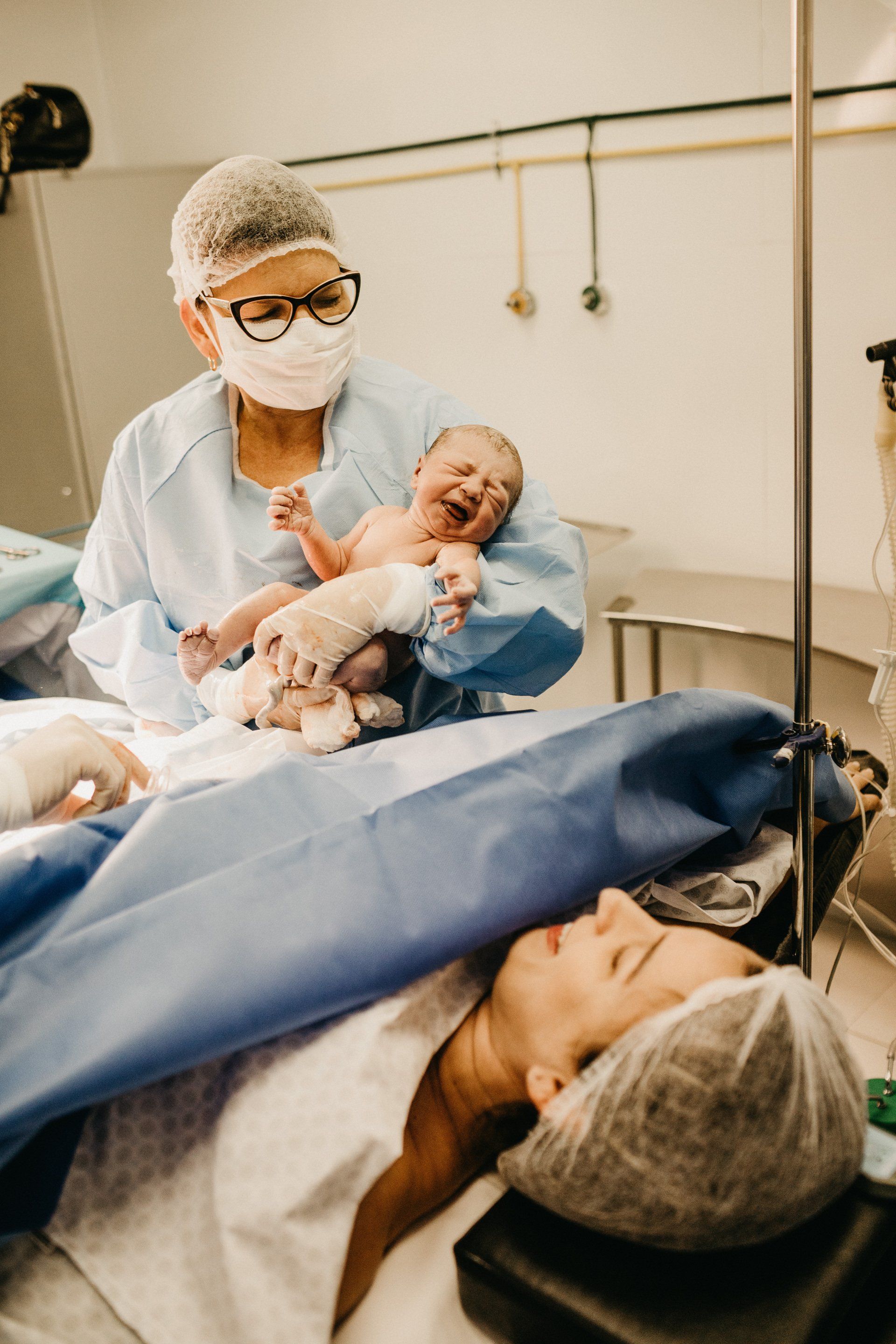 A woman is laying in an operating room holding a newborn baby.