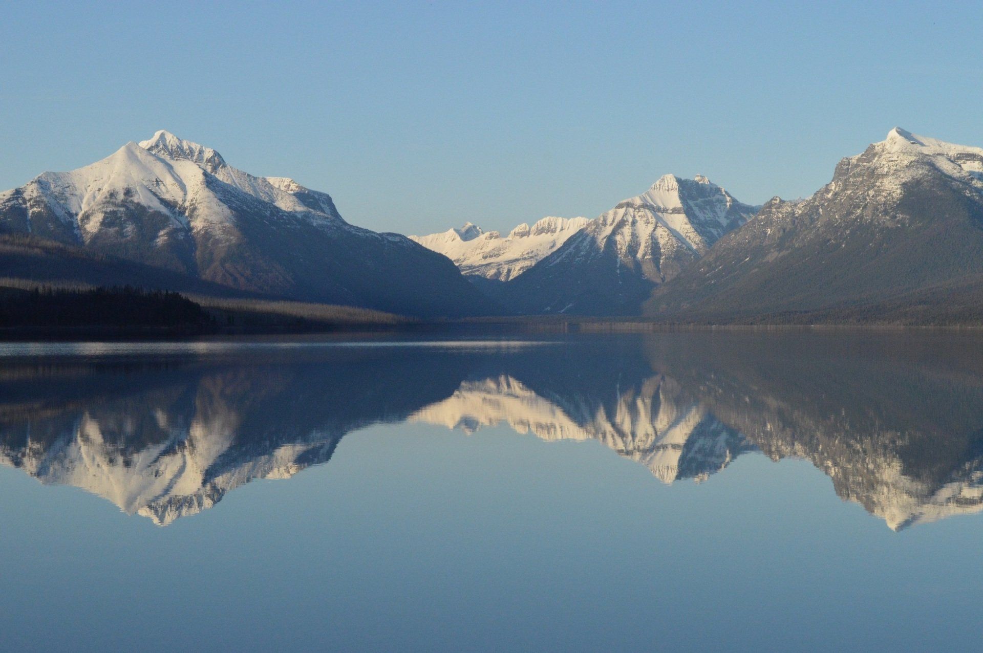 A lake with mountains in the background and mountains reflected in the water