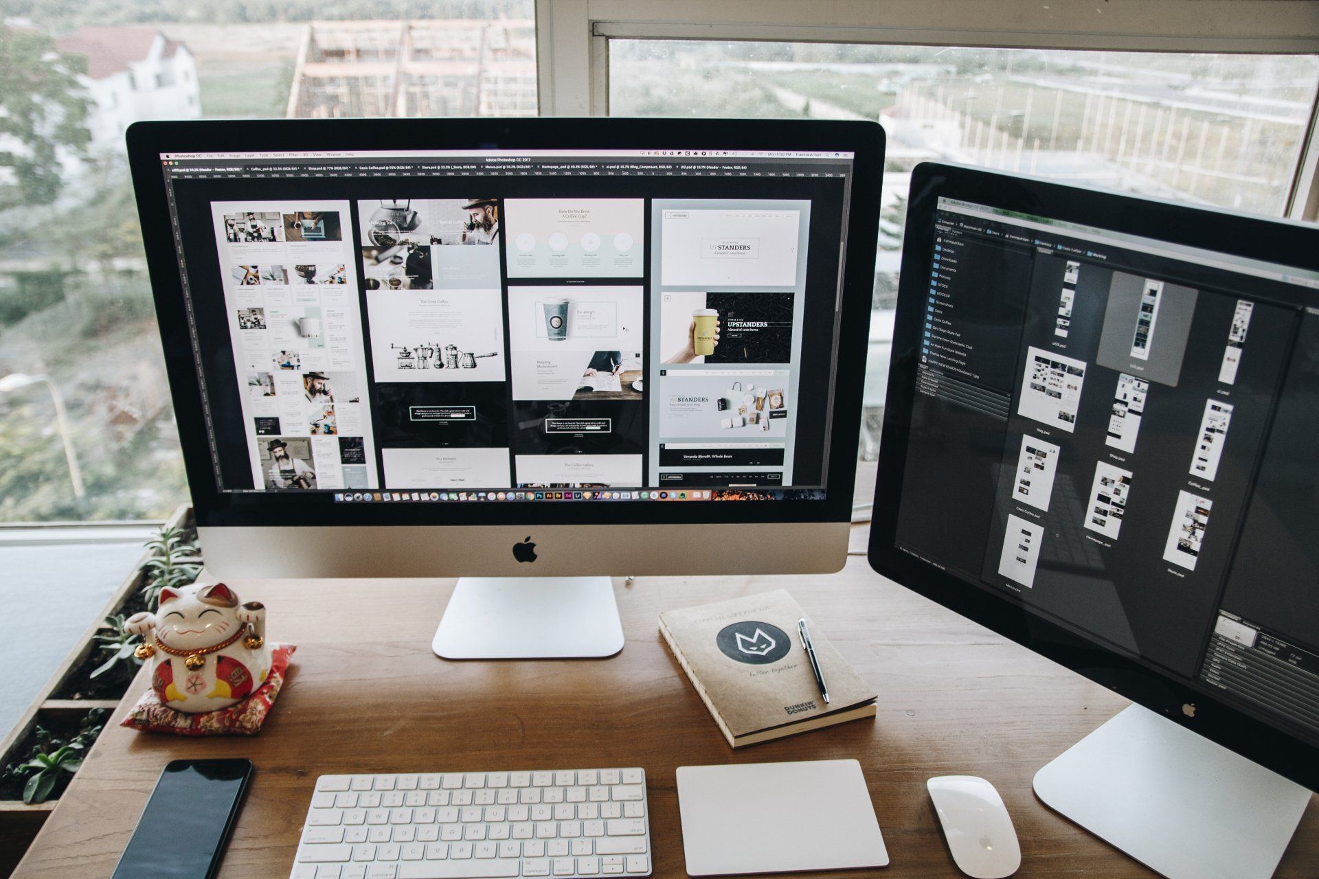 Image of two apple monitors & iPhone with a keyboard & mouse placed on an office desk