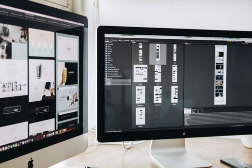 Two computer monitors are sitting next to each other on a desk.