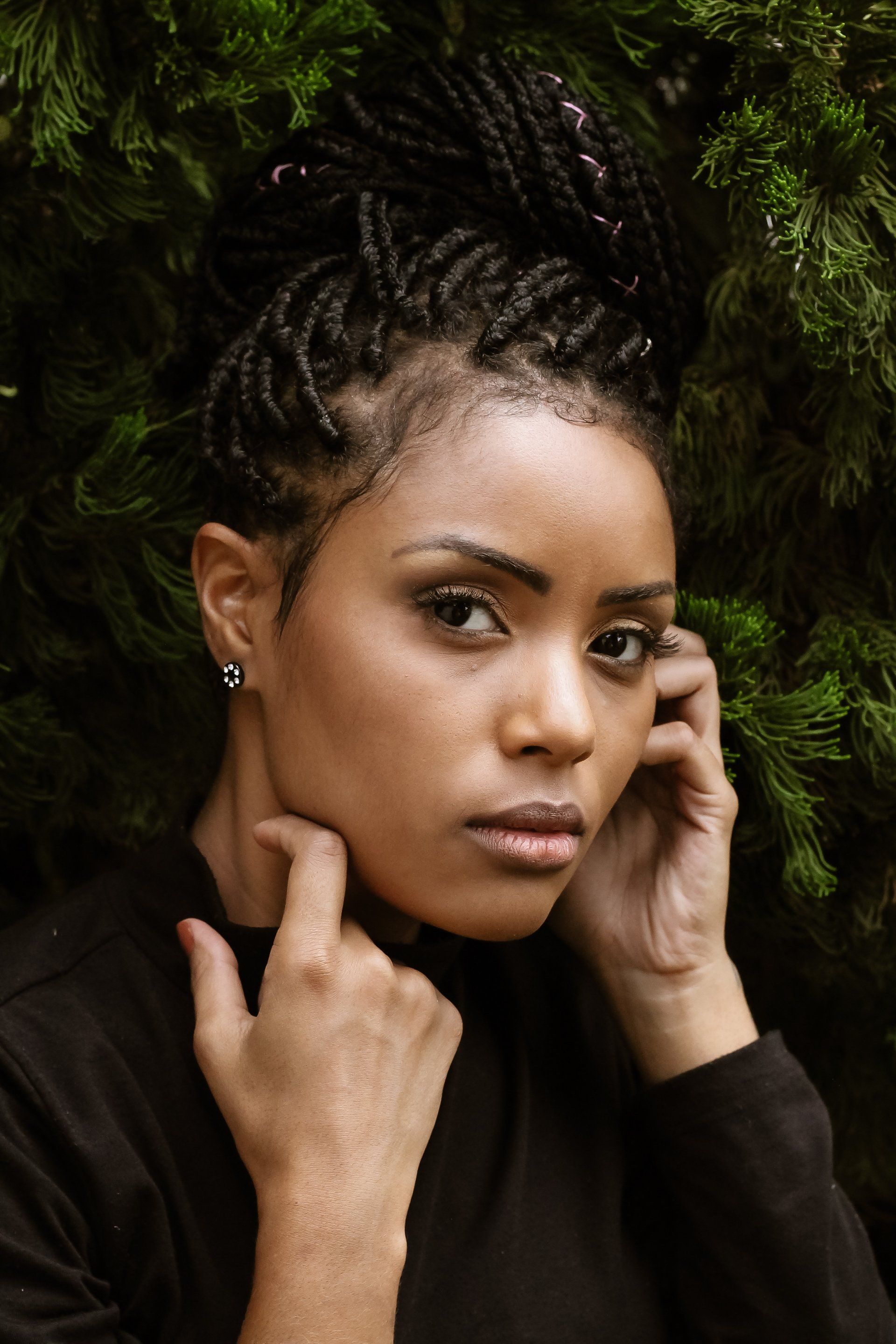 A black woman with braids in her hair is touching her face.