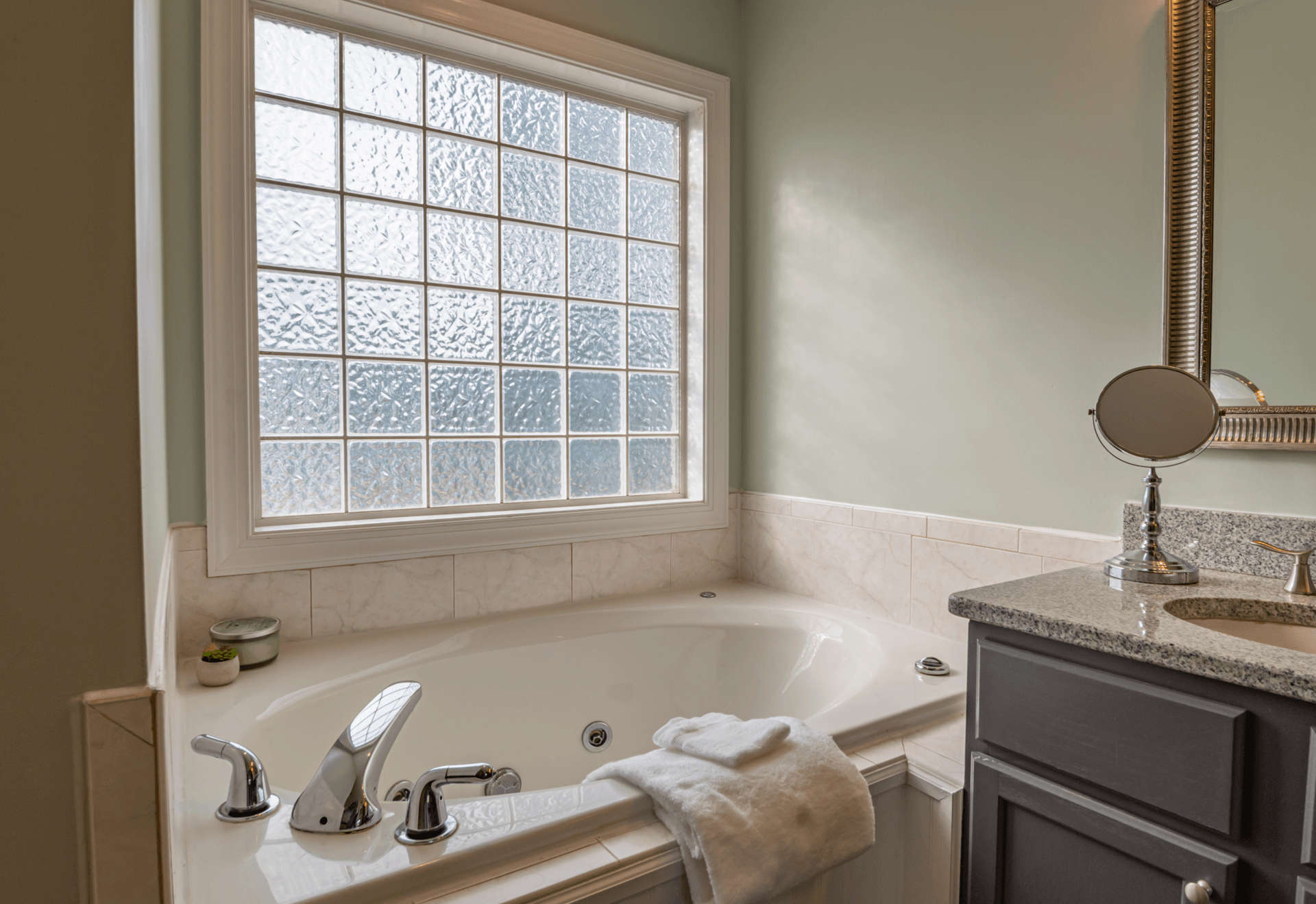 a bathroom makeover 2024 with a jacuzzi tub, sink , mirror, and window 