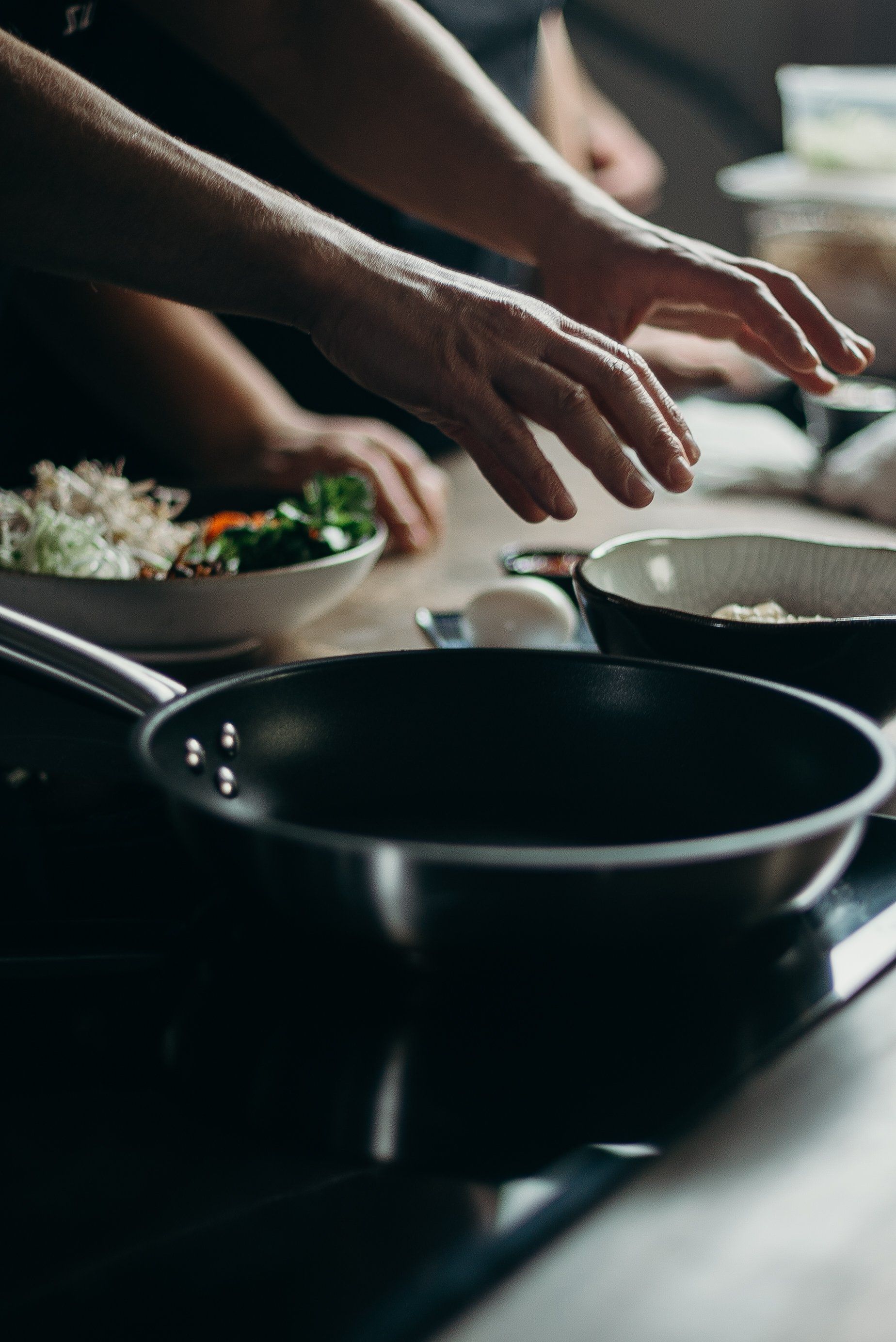 a person is reaching into a frying pan on a stove .